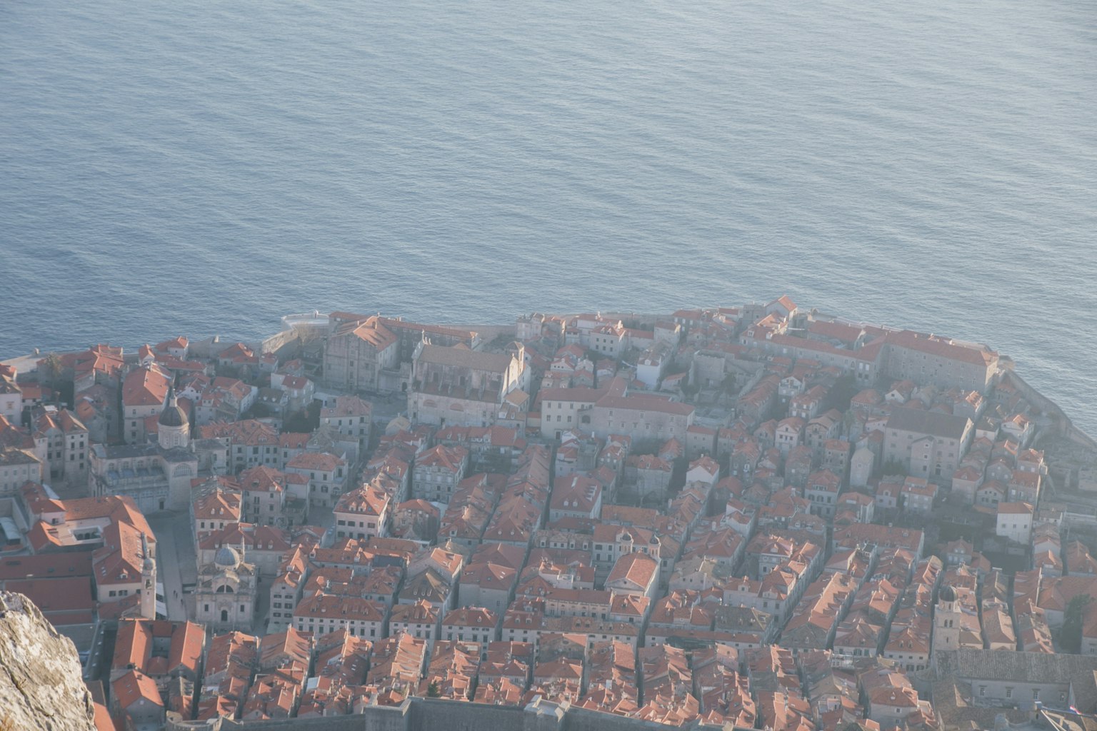 Aerial view of a coastal town with densely packed red-roofed buildings