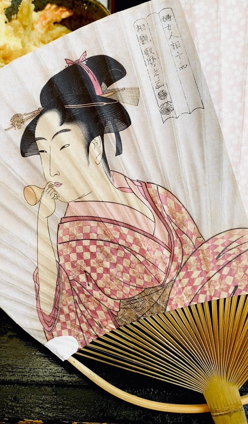 うちわに描かれた浮世絵の女性と扇子のあるテーブル