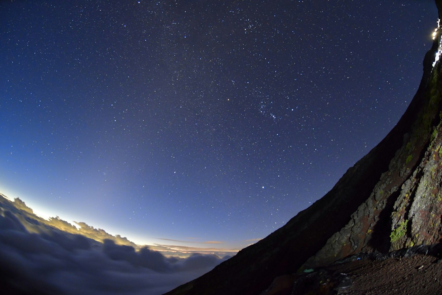 Atemberaubende Aussicht auf einen Sternenhimmel über einem Wolkenmeer an einem Berghang