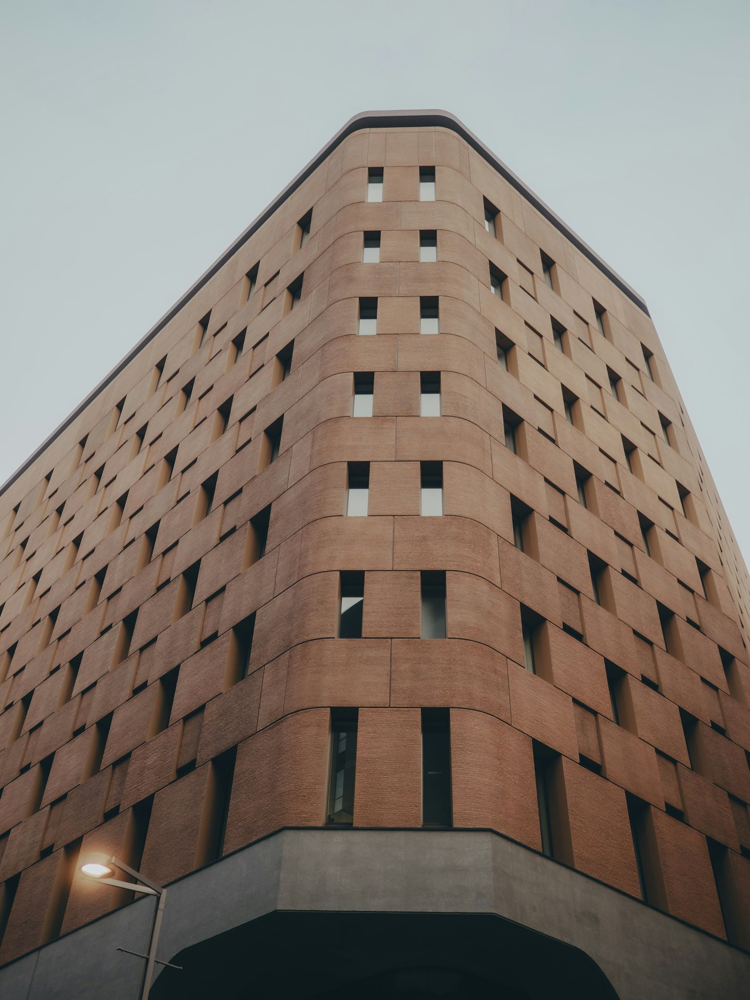 Bâtiment moderne avec façade angulaire lampadaire et ciel nuageux