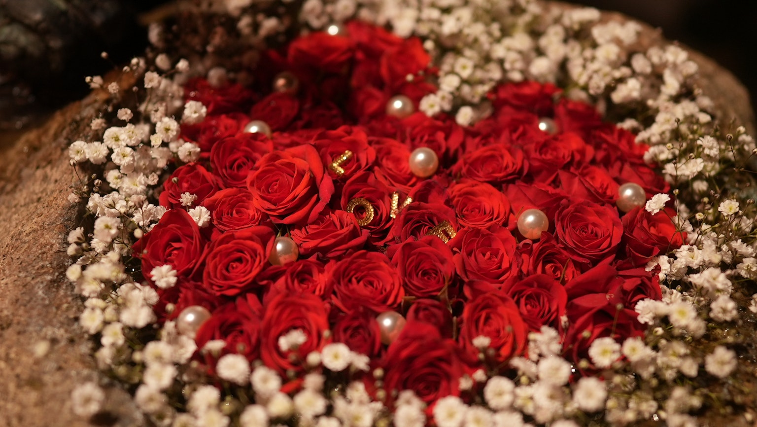 Arrangement en forme de cœur de roses rouges et de petites fleurs blanches