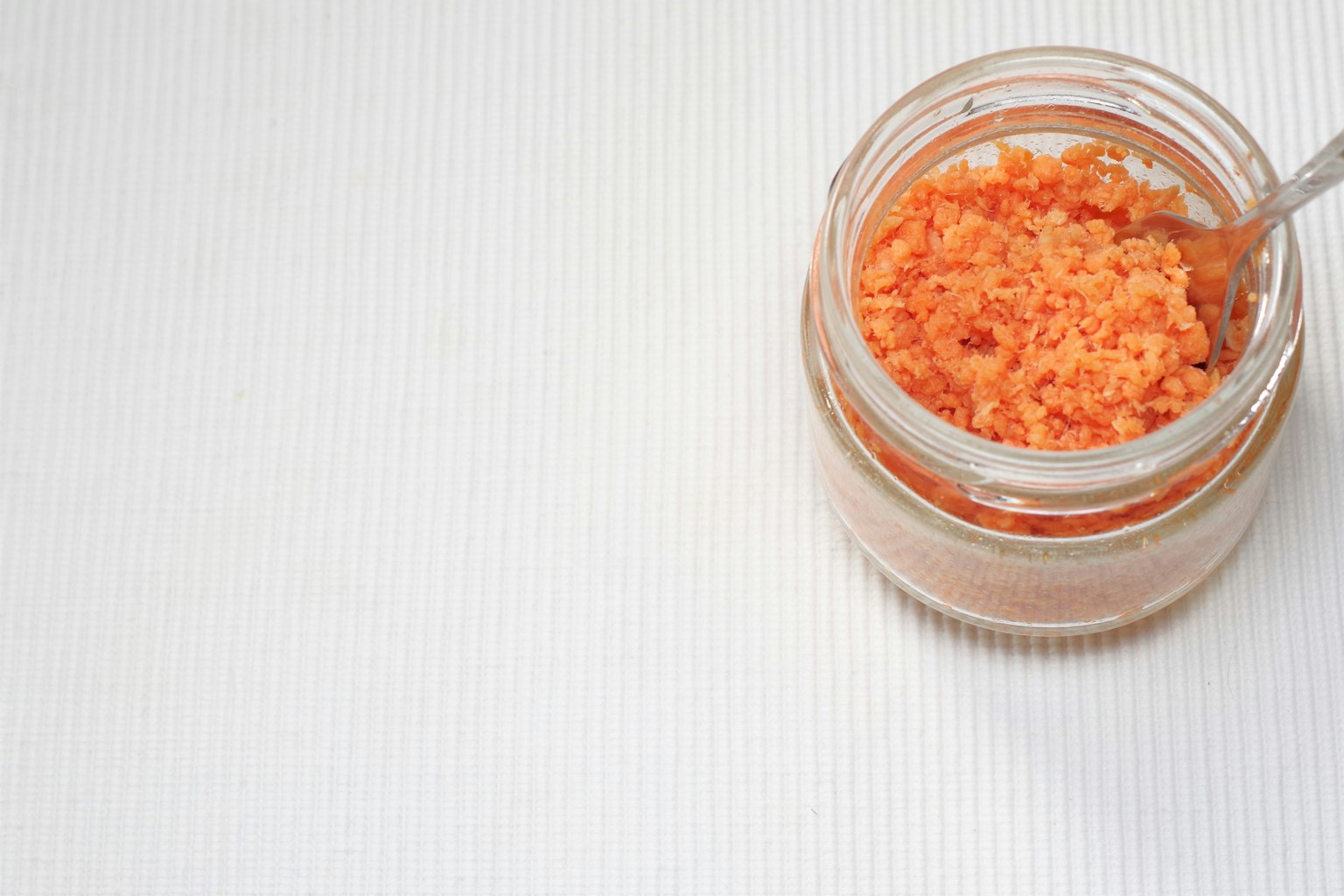 Barattolo di vetro riempito di sale arancione con un cucchiaio