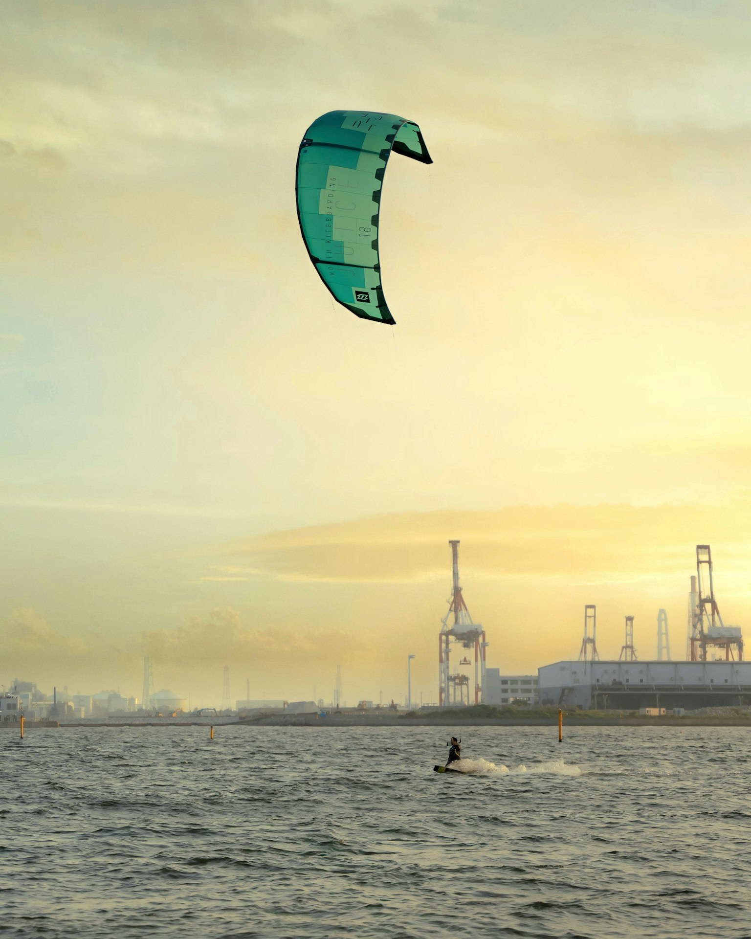 Kitesurfer sull'acqua con uno skyline industriale sullo sfondo