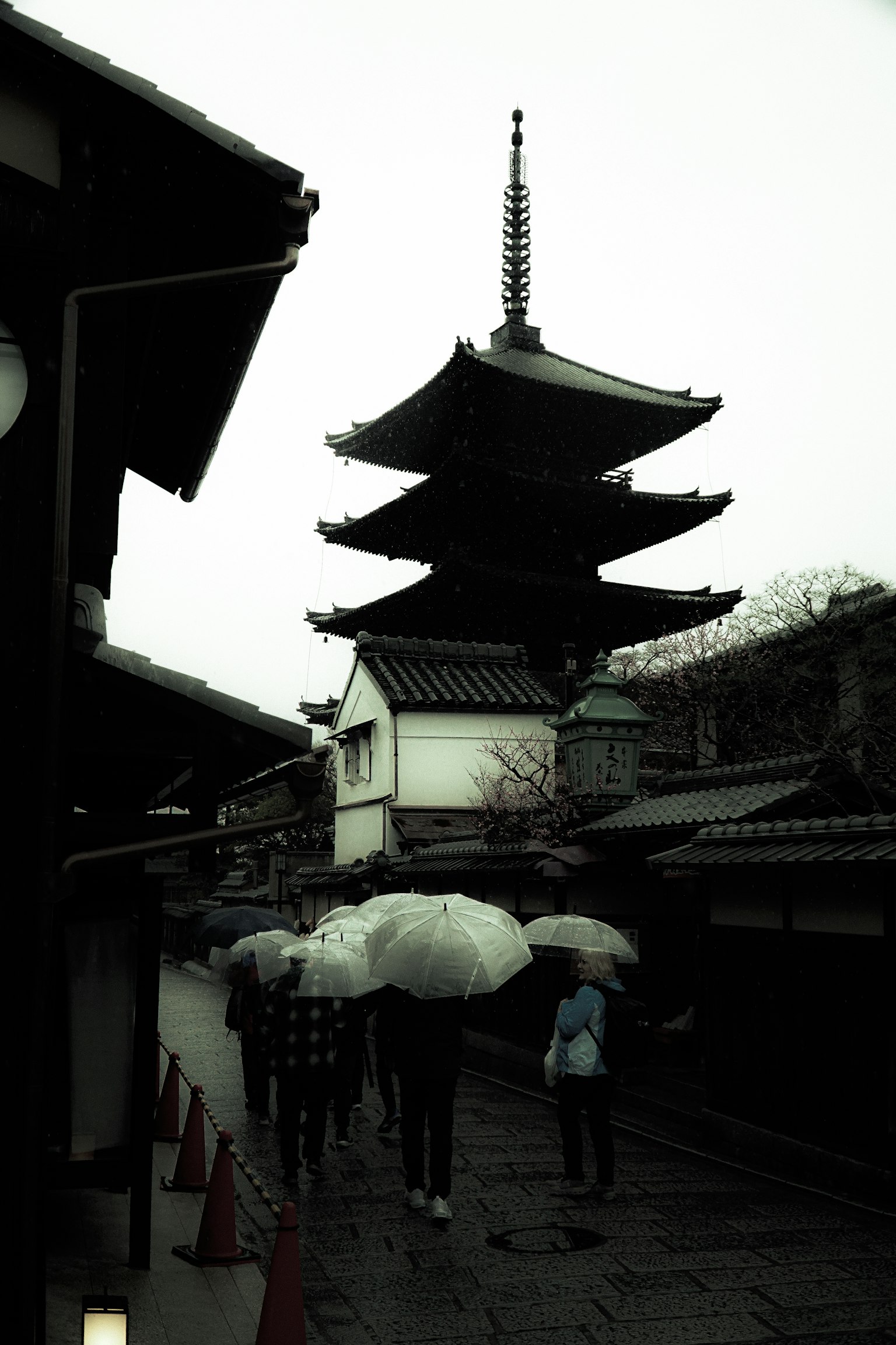 Scene of a pagoda with people holding umbrellas in the rain