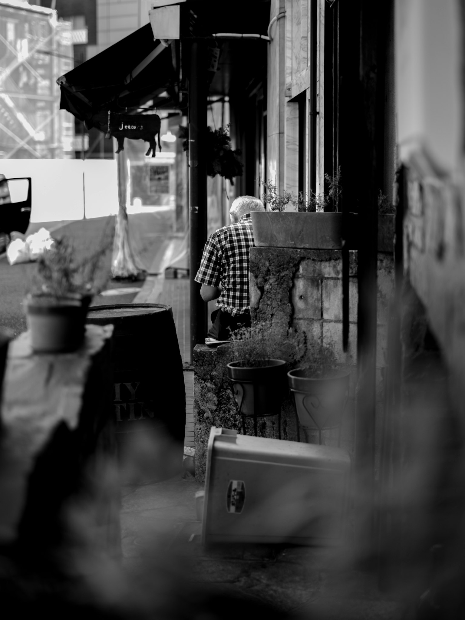 ภาพถนนสีดำขาวที่มีคนใส่เสื้อเชิ้ตลายตารางนั่งหันหลัง