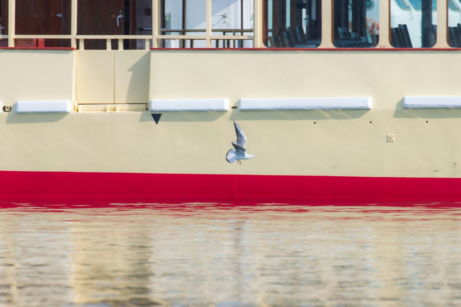 Image featuring a boat's yellow and red side with a reflection on the water