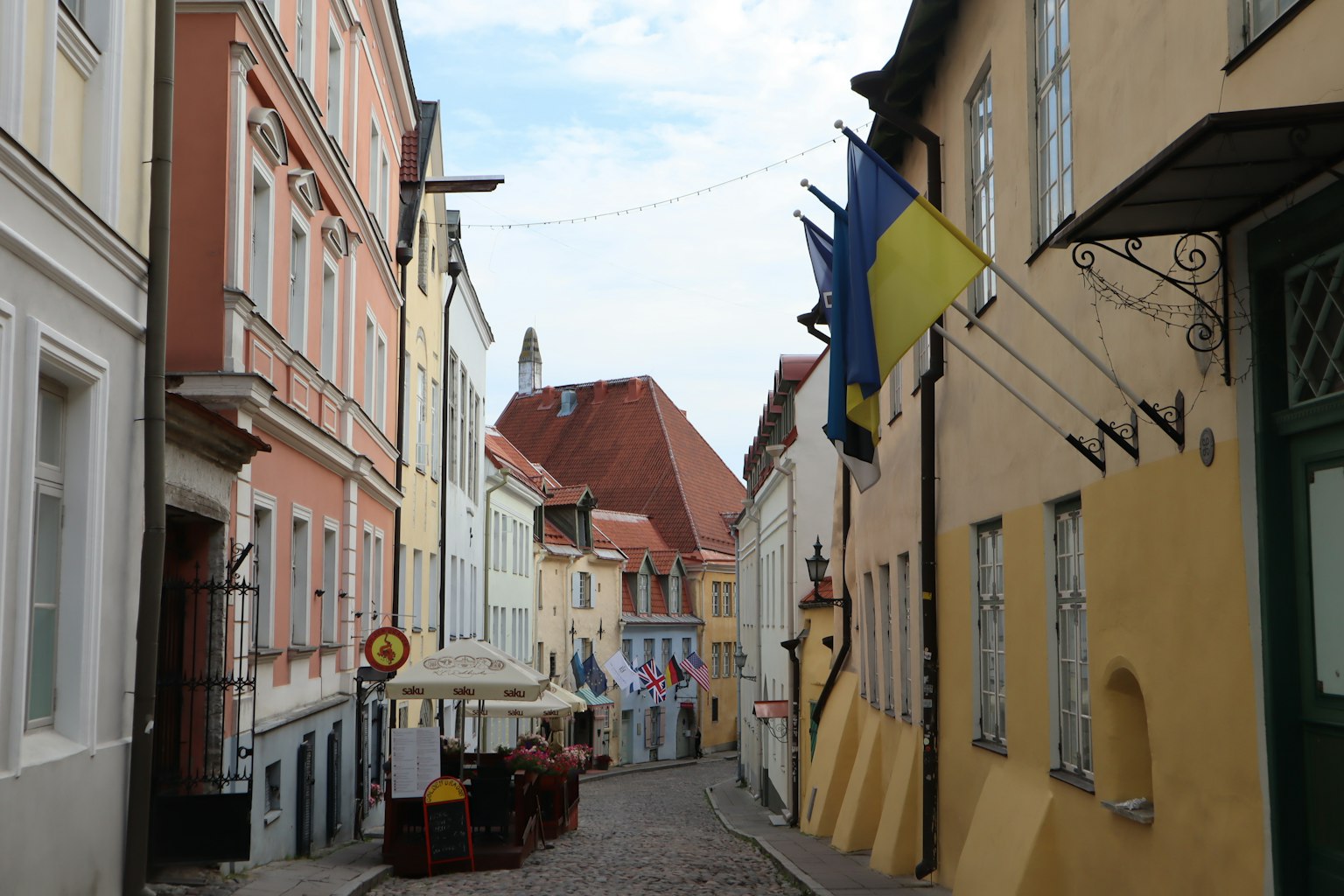 Narrow street lined with colorful buildings featuring Ukrainian flags
