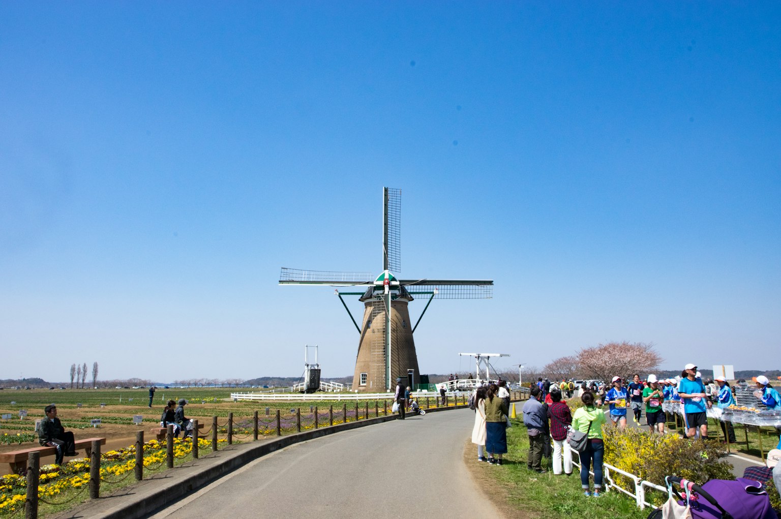Vista escénica de un molino de viento bajo un cielo azul claro con visitantes cercanos