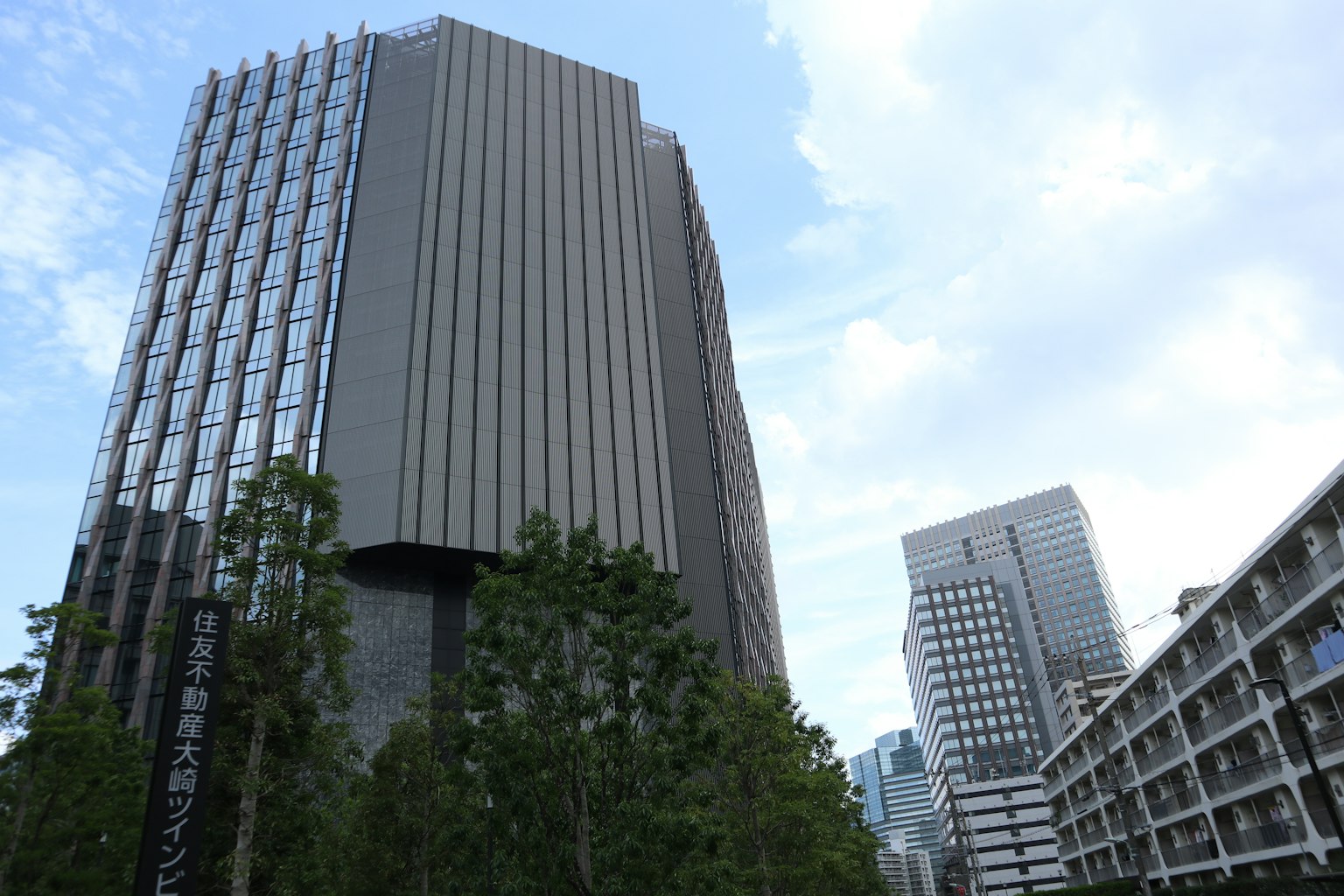 Urban landscape featuring modern skyscrapers and green trees under a blue sky