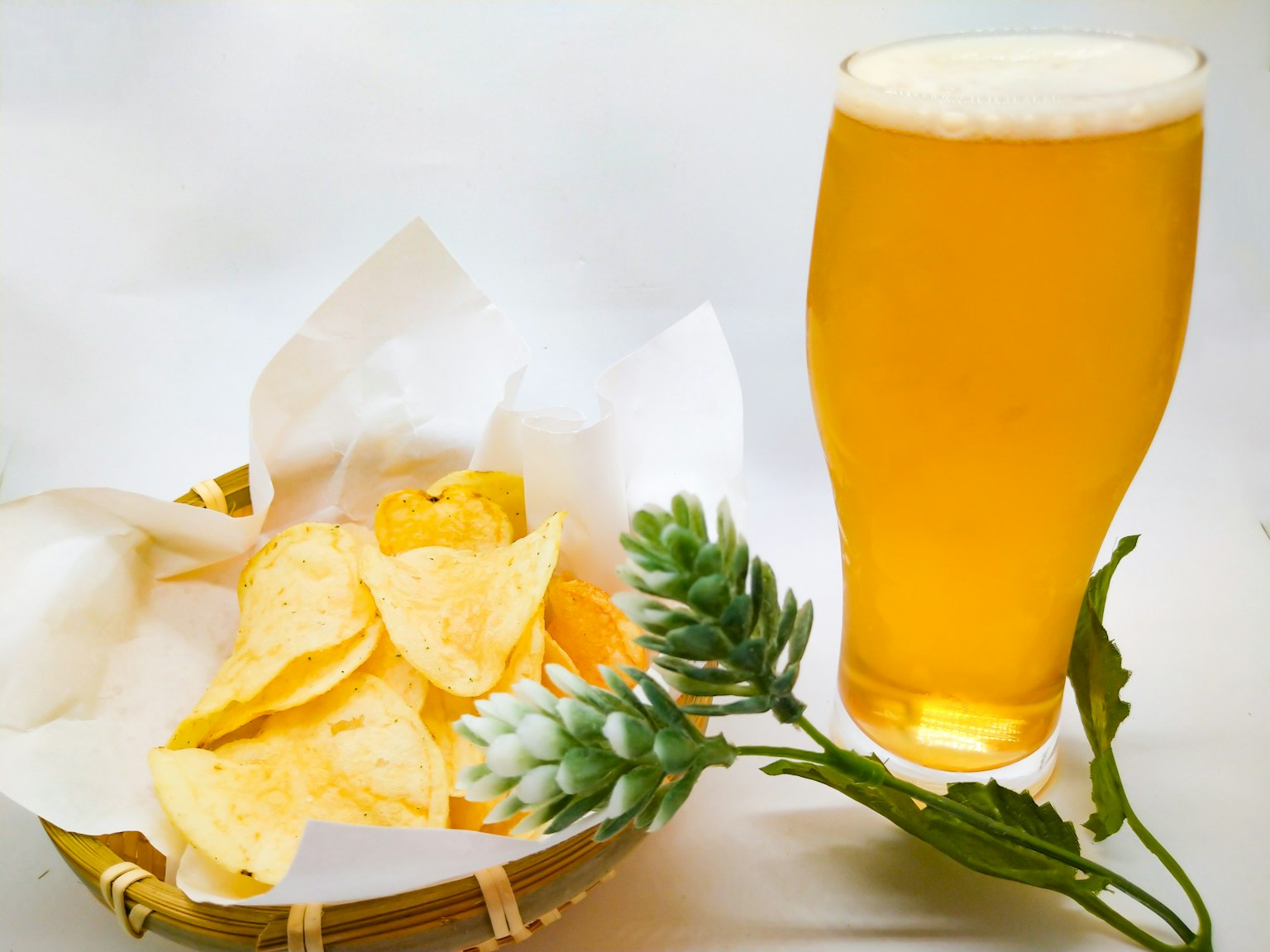 Panier de chips de pomme de terre à côté d'un verre de bière dorée