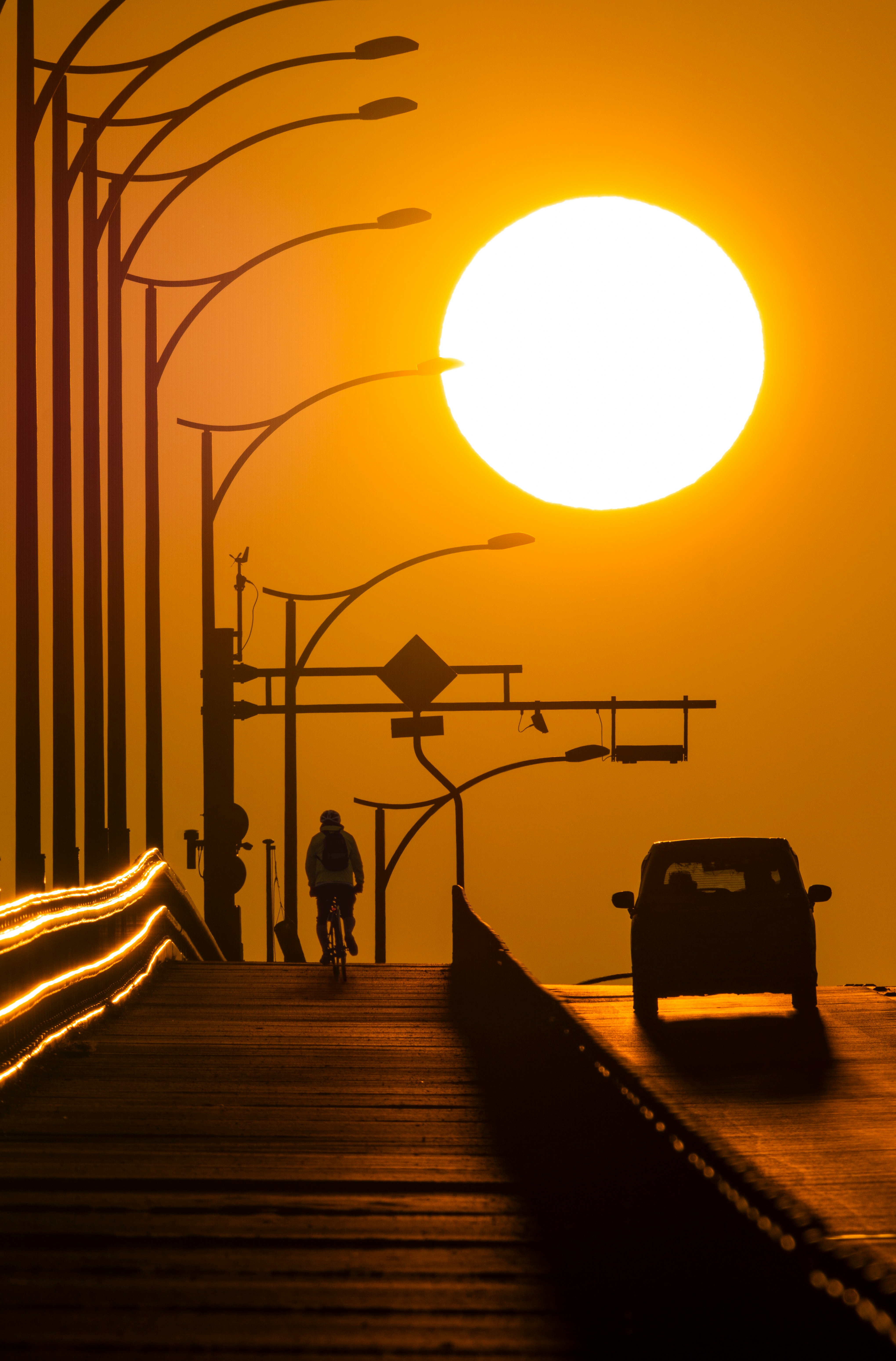 paseo marítimo con farolas en silueta frente al atardecer