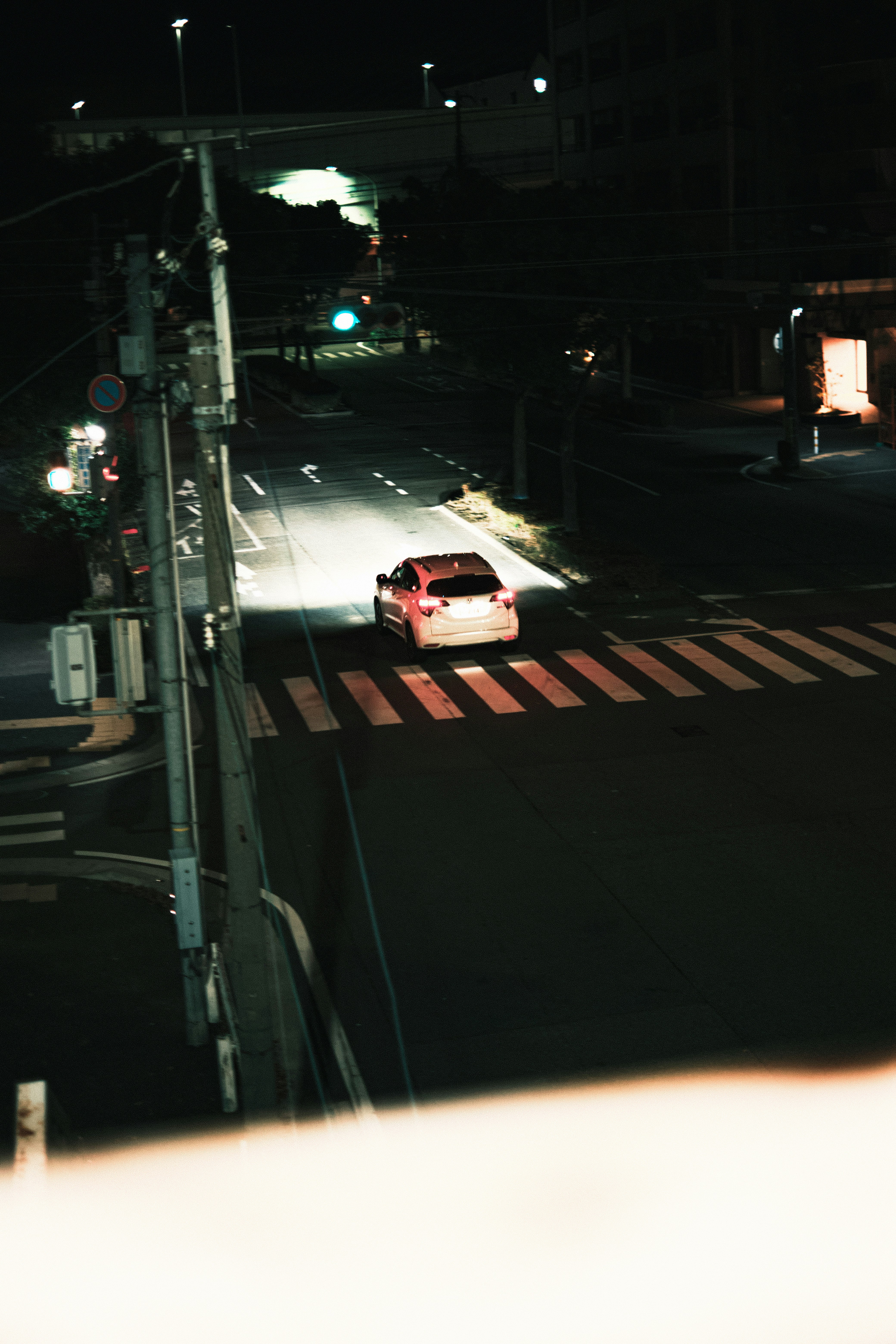 夜の交差点で走る白いスポーツカー