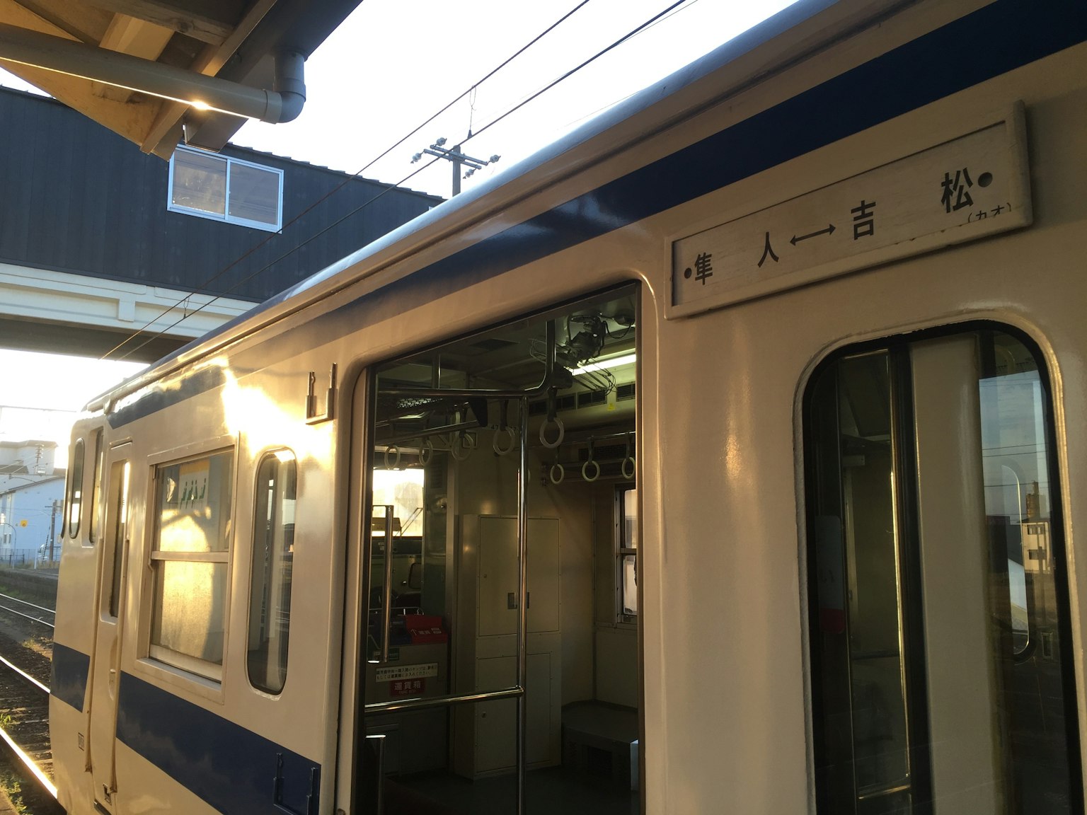Side view of a train at a station with a station name sign
