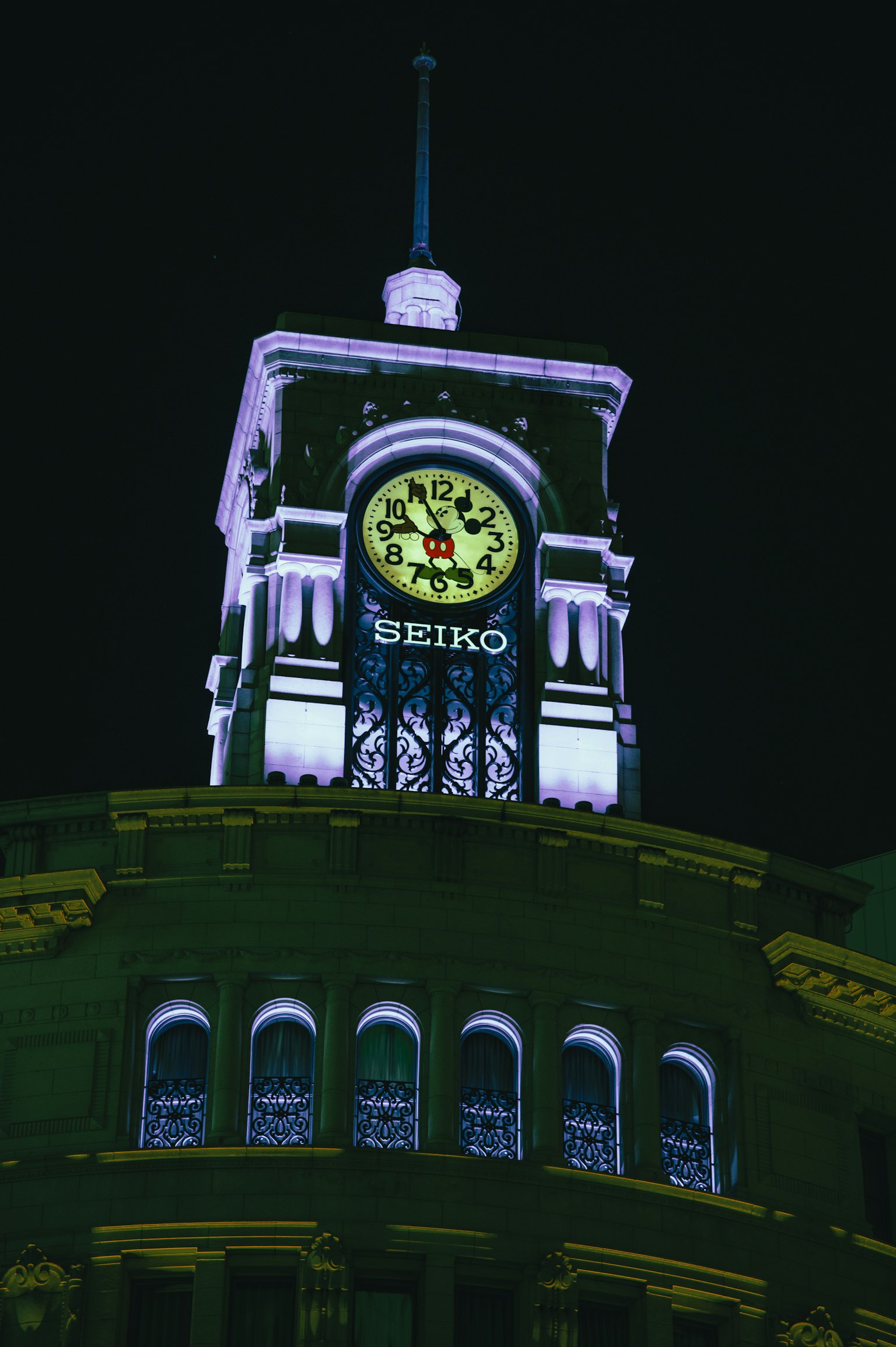 Seiko clock shining on the top of a building at night