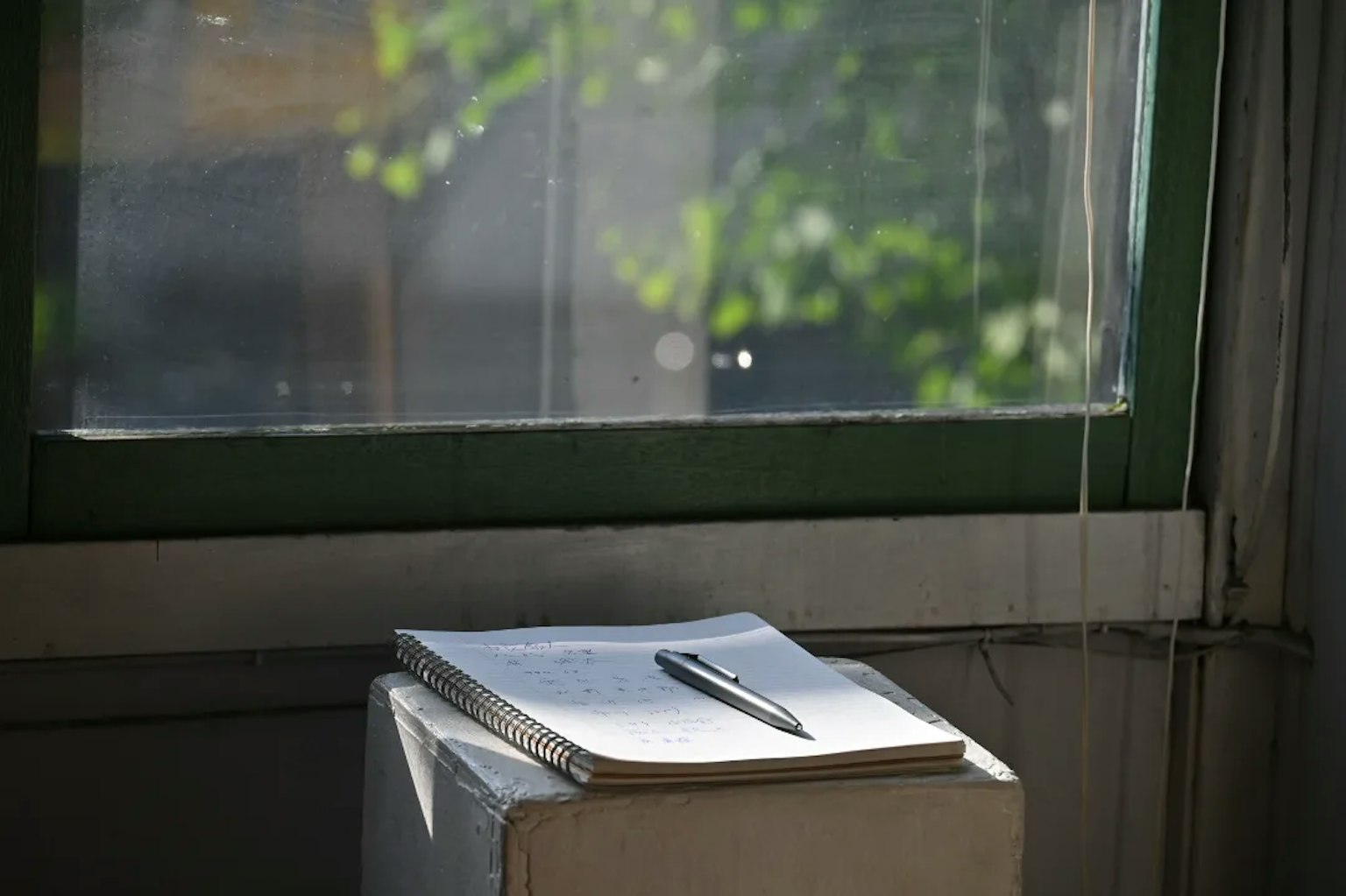 Eine weiße Box mit einem Notizbuch und einem Stift neben einem Fenster