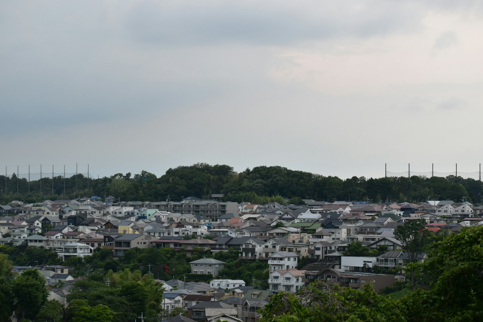 夕方の曇天の住宅街と遠景の丘