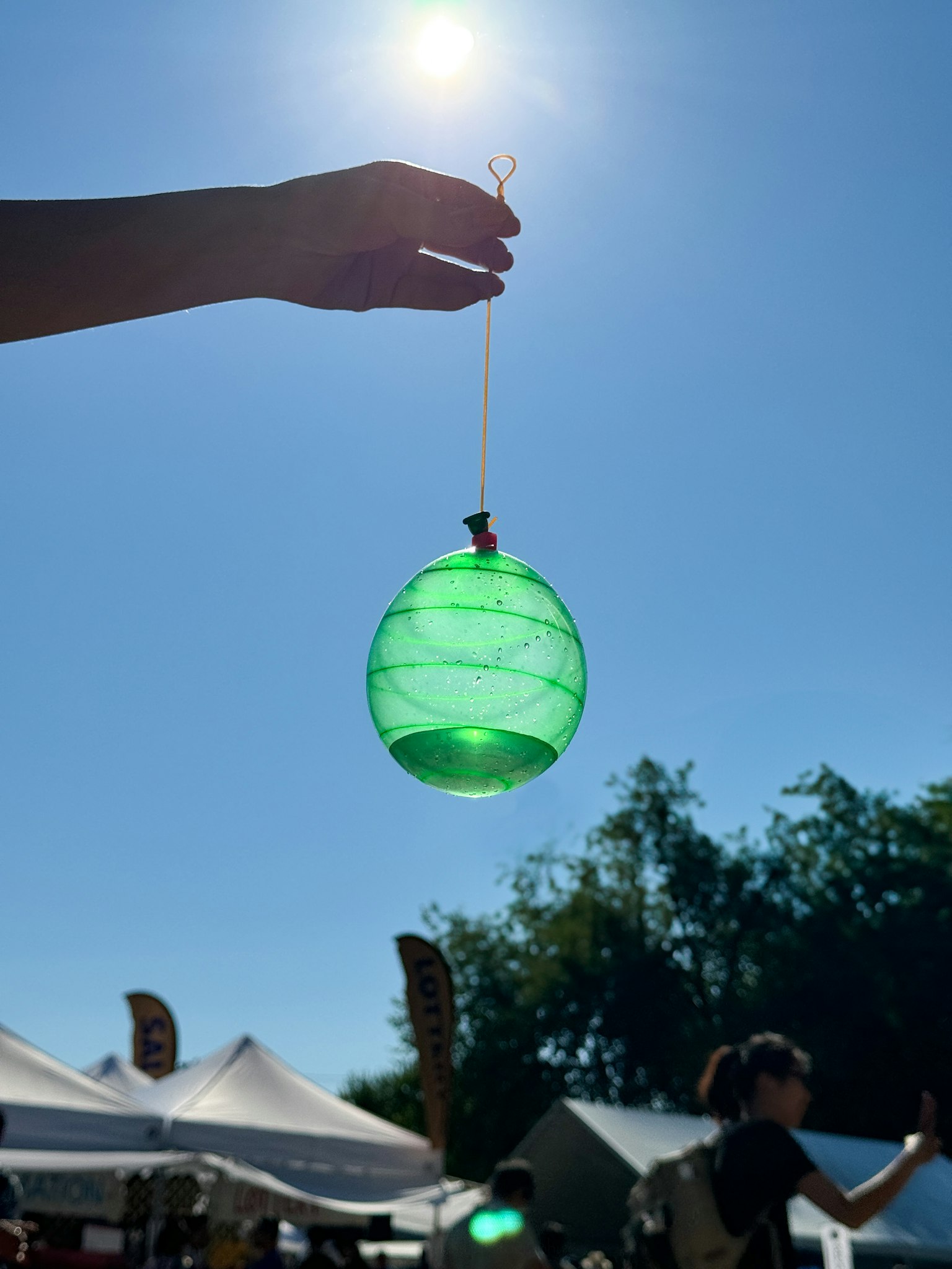 A hand holding a green spherical object illuminated by sunlight