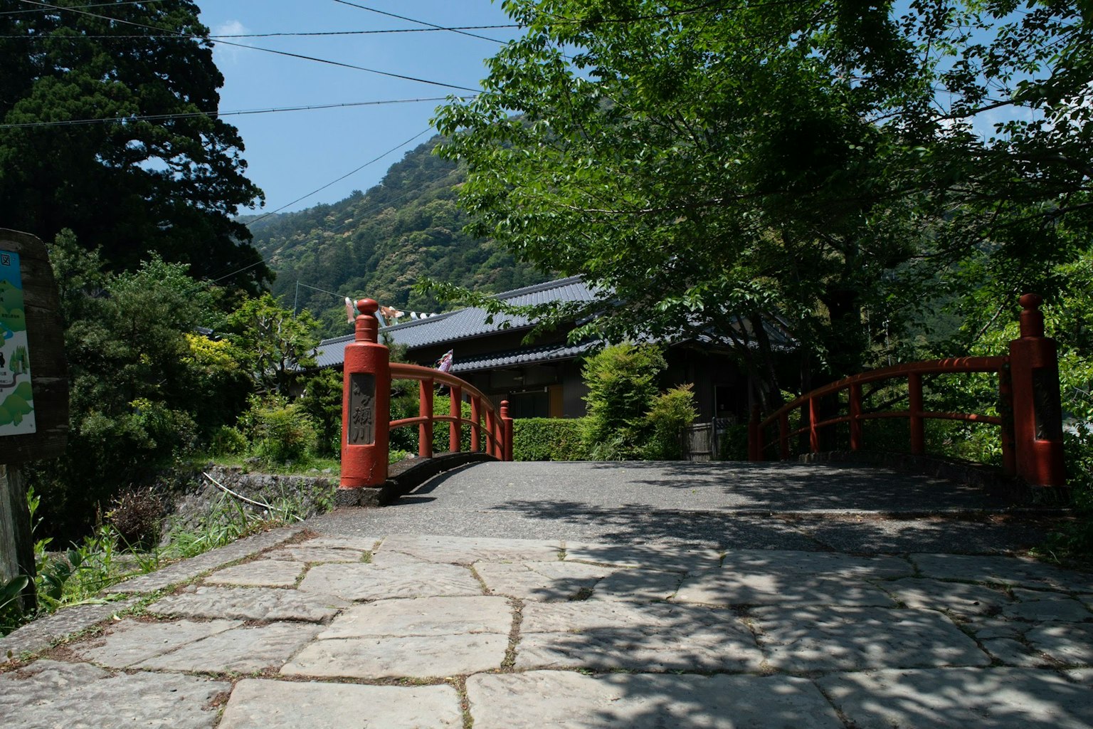 Casa japonesa tradicional rodeada de naturaleza con un puente rojo