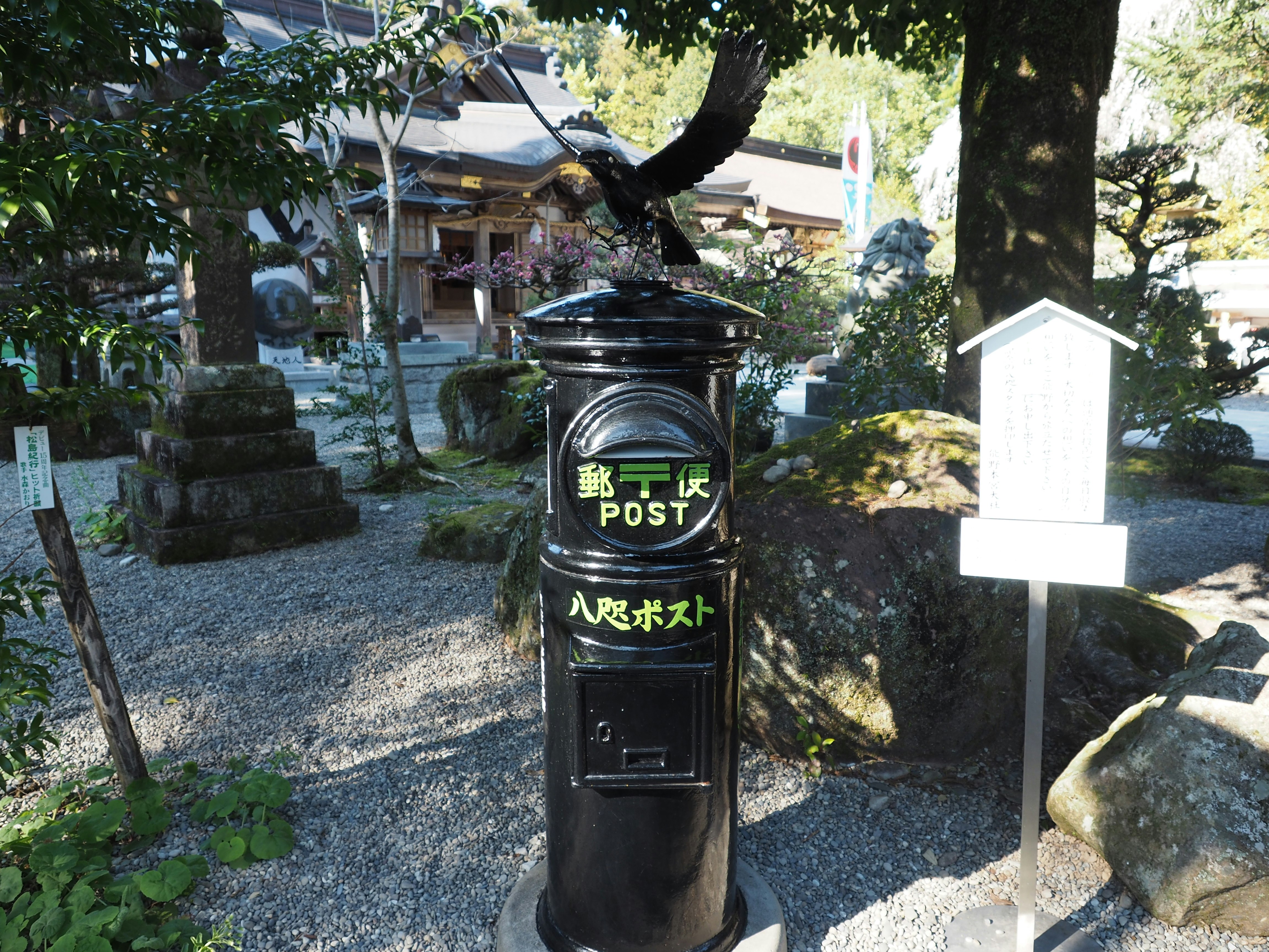 庭園の小道に置かれた郵便ポストと黒い鳥の看板「八咫烏」