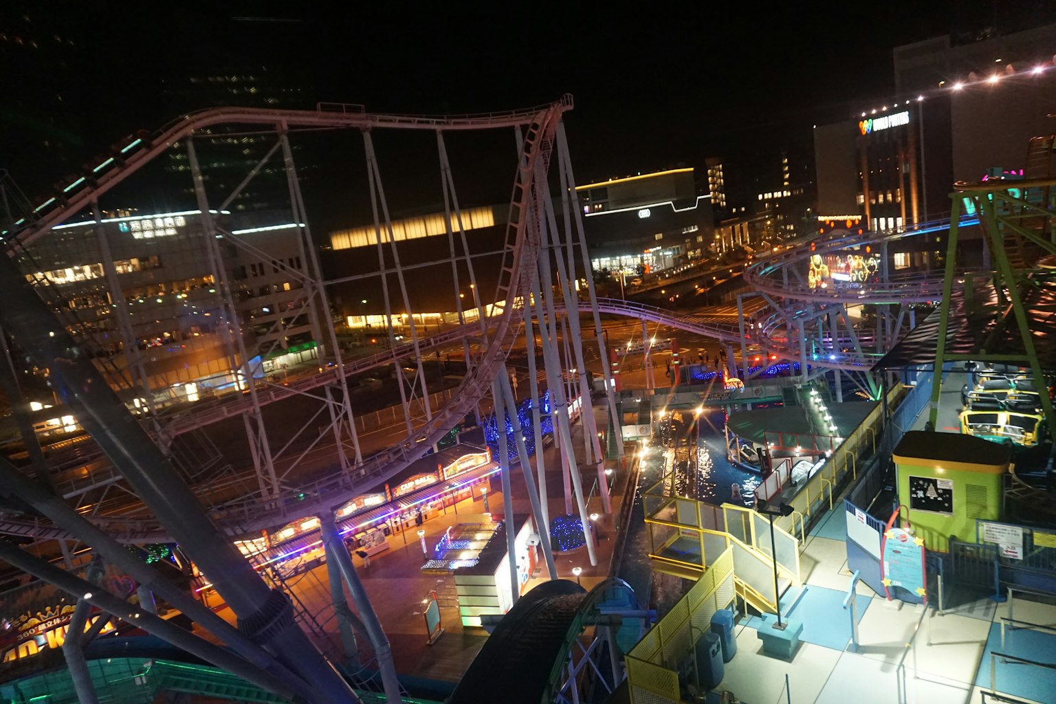 Pemandangan malam taman hiburan dengan roller coaster yang diterangi