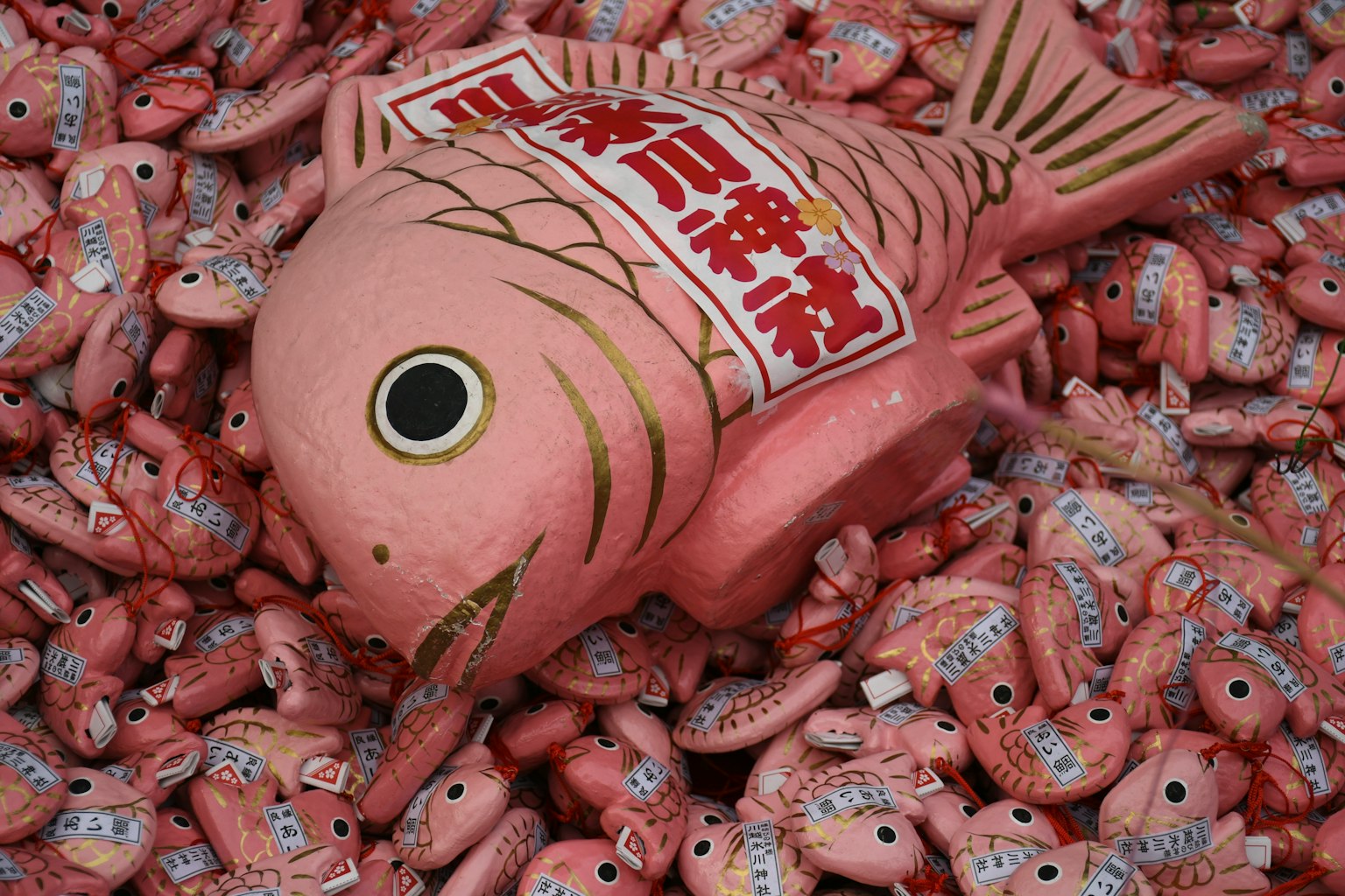A large pink fish decoration surrounded by numerous smaller fish decorations