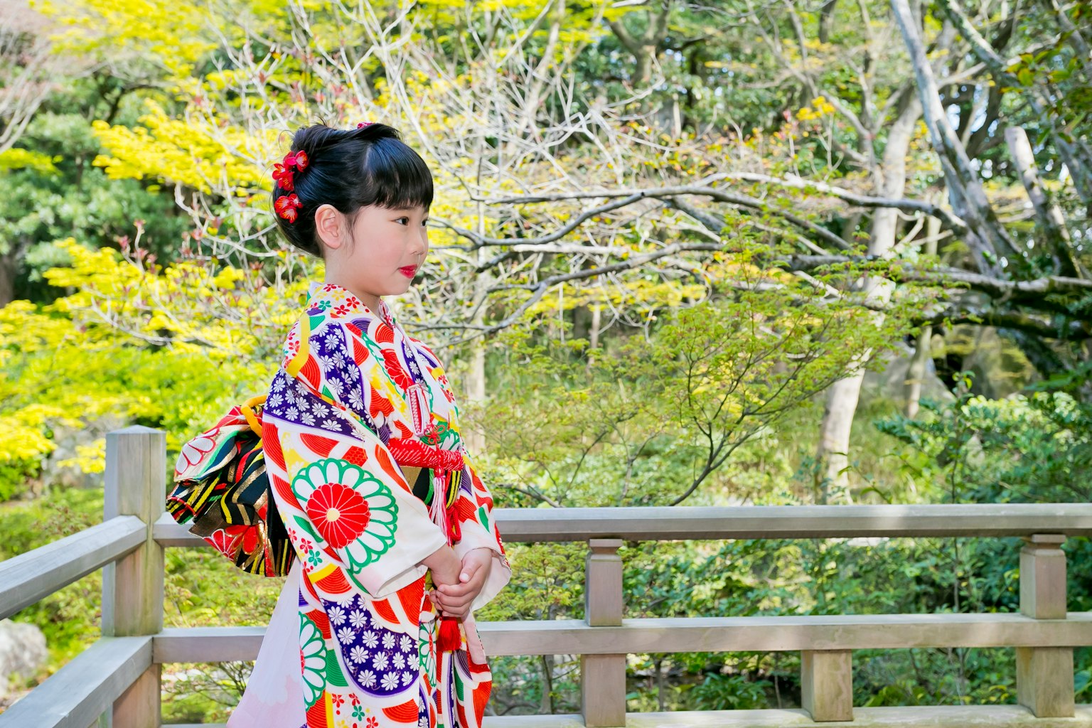 เด็กหญิงในชุดกิโมโนสีสันสดใสยืนอยู่ในบรรยากาศธรรมชาติ