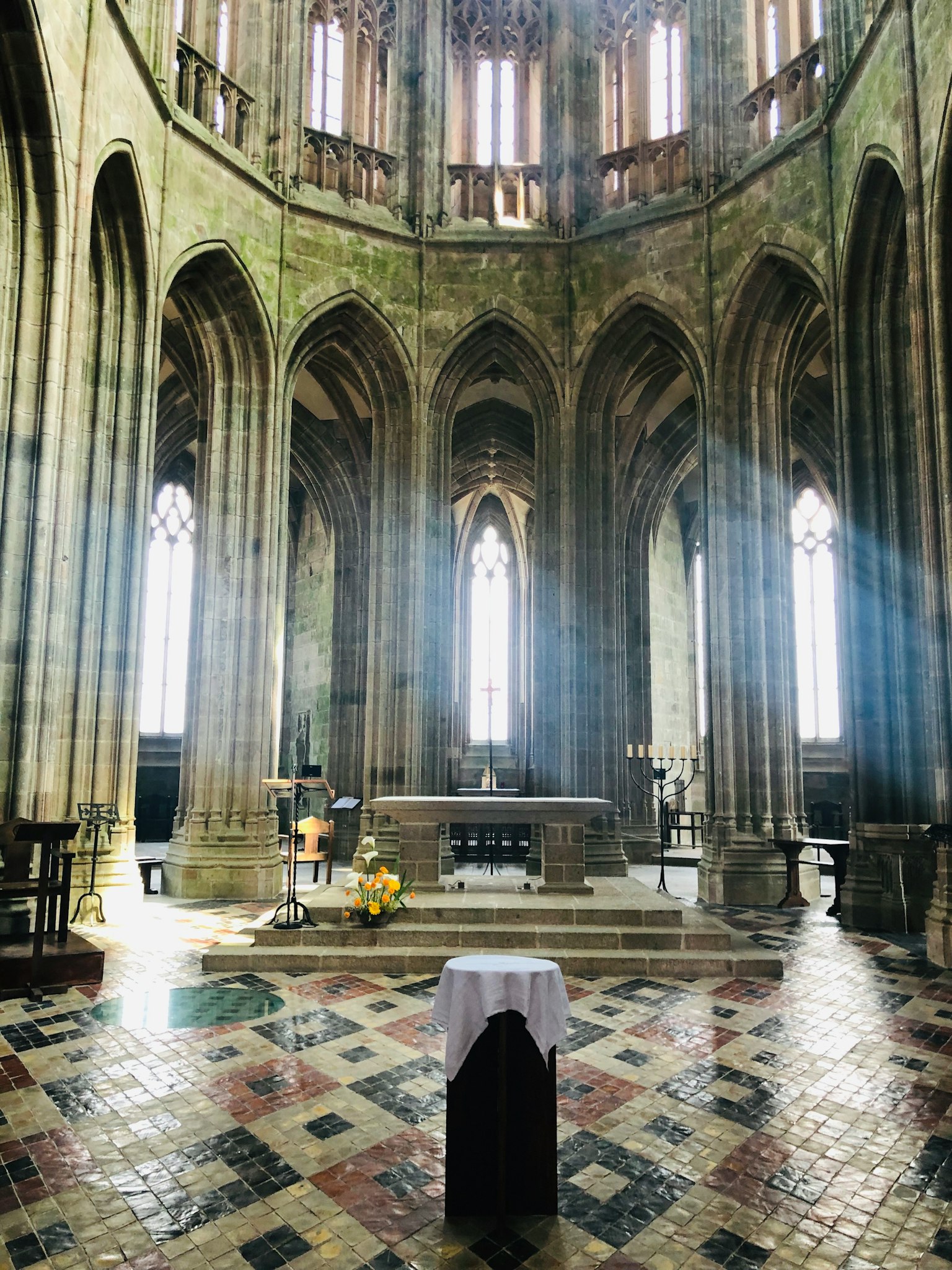 Majestuoso interior de iglesia con techo arqueado que deja entrar la luz suelo de azulejos coloridos con una mesa blanca y un paño negro en el centro