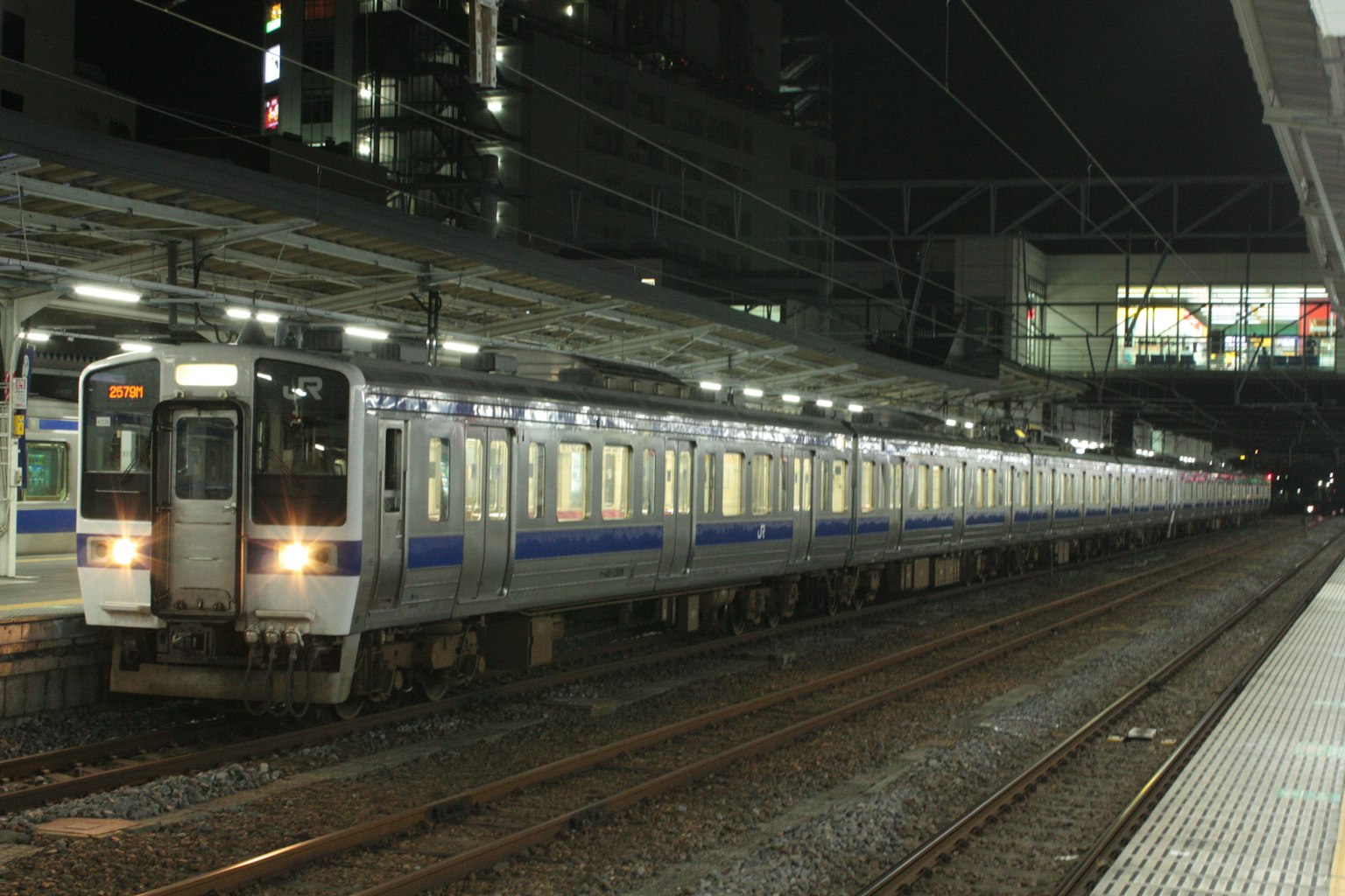 Kereta biru dan putih berhenti di stasiun pada malam hari