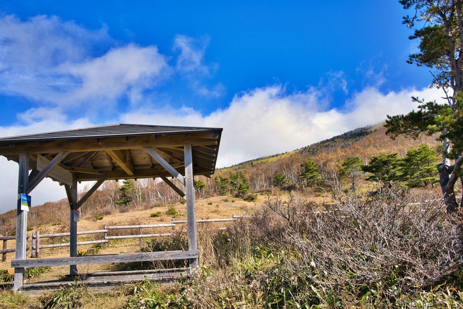 Gazebo in legno sotto un cielo blu con sfondo montano