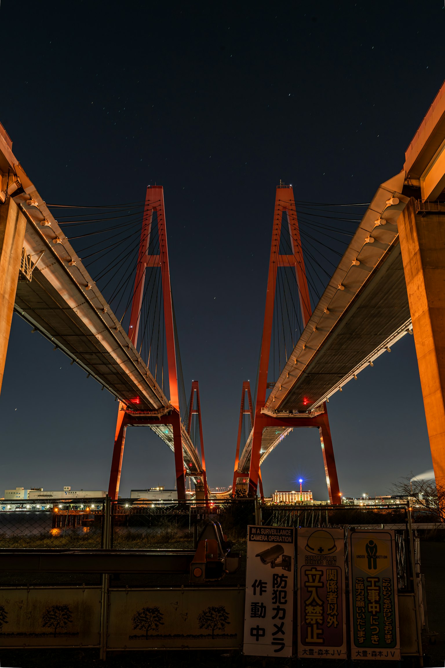 Vista desde abajo de un puente colgante rojo por la noche destacando sus características arquitectónicas