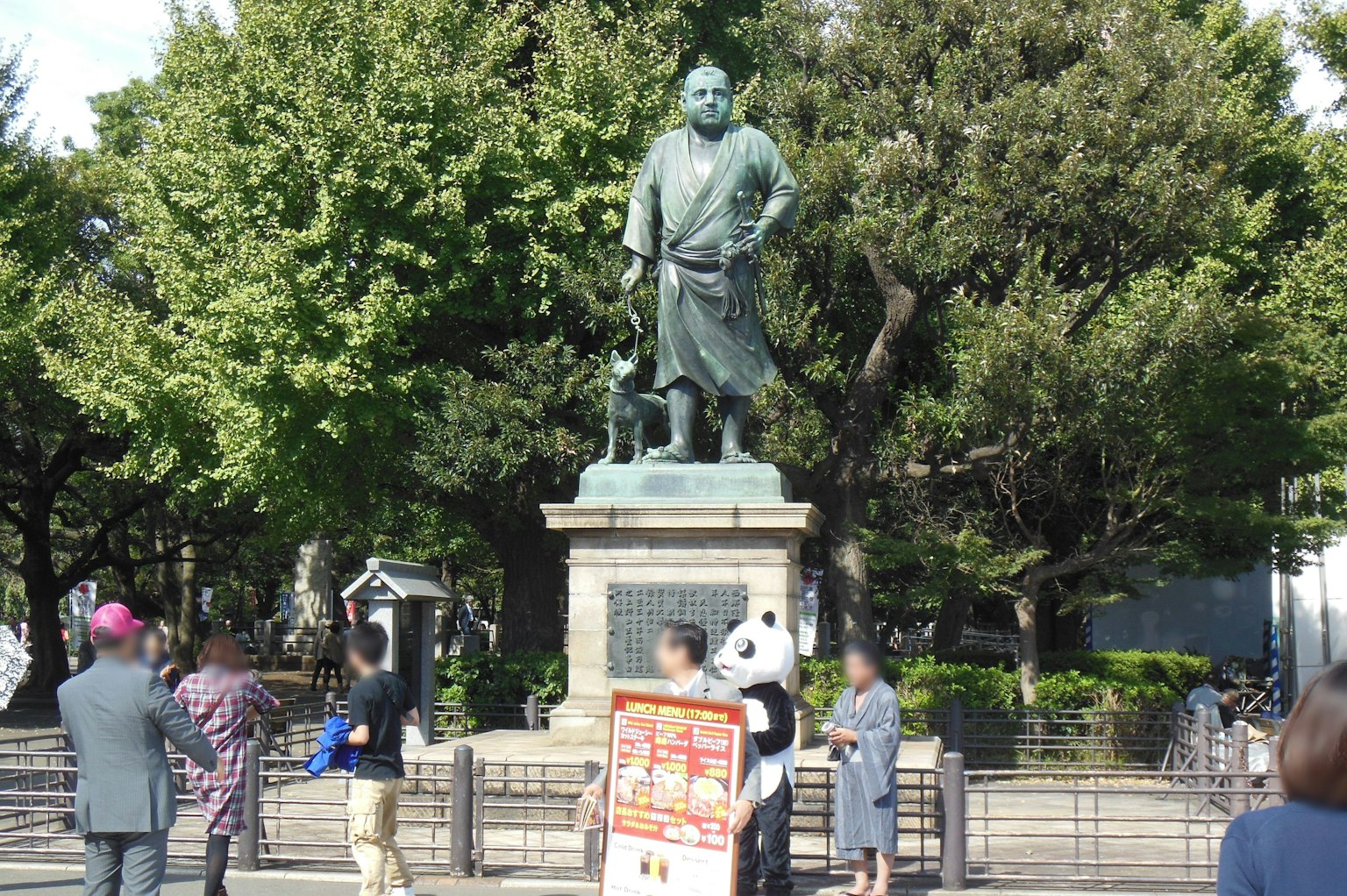 Estatua de bronce histórica en un parque con personas cercanas