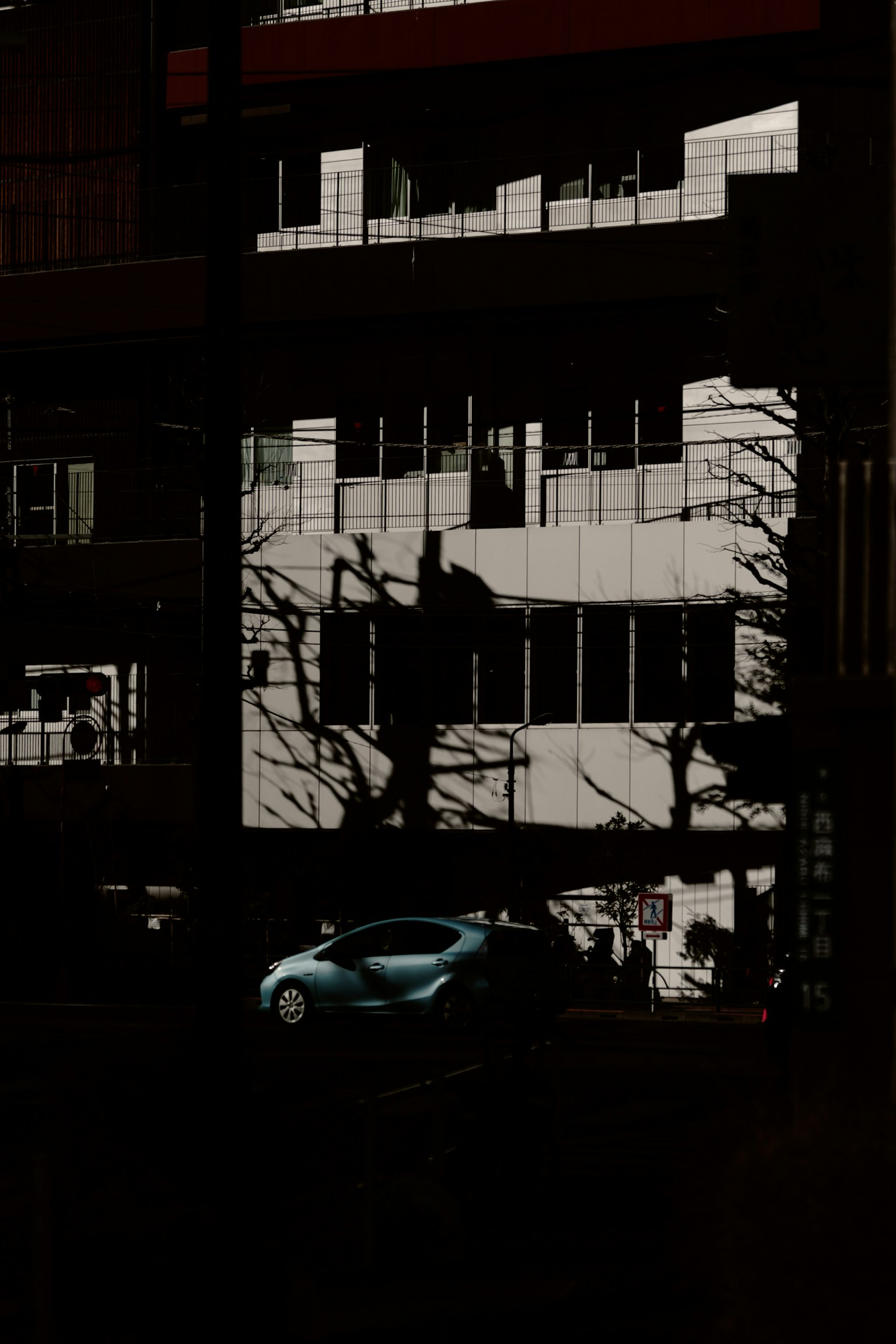 Gebäudeschatten mit einem blauen Auto, das in dunkler Umgebung reflektiert wird