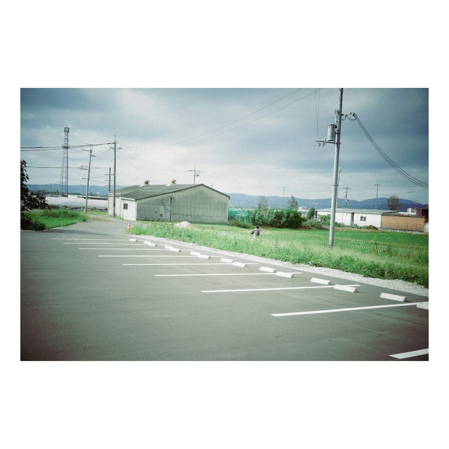 空の青と緑の草地が広がる駐車場の風景