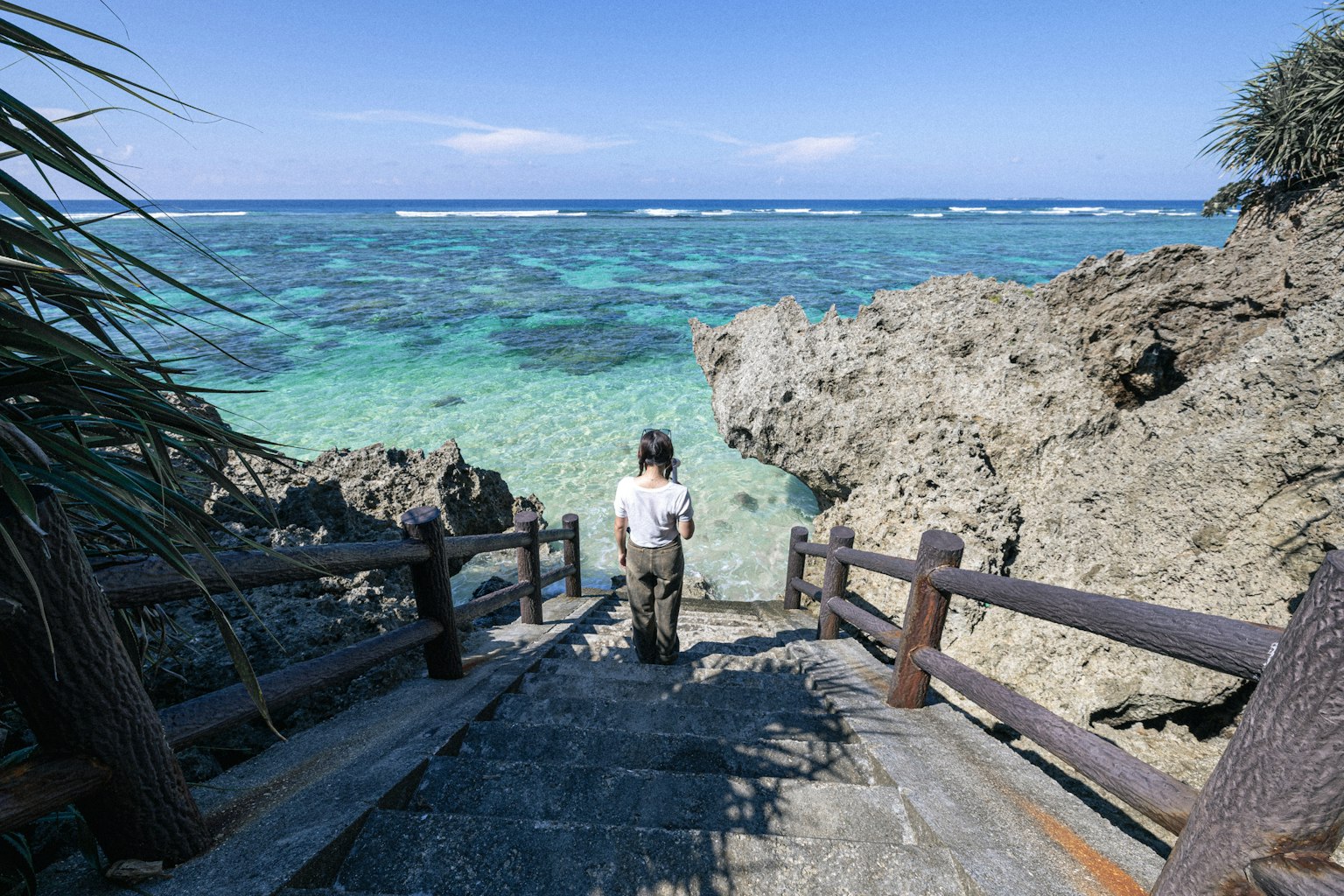 女性走下石階，通往碧綠色的海洋和岩石海岸