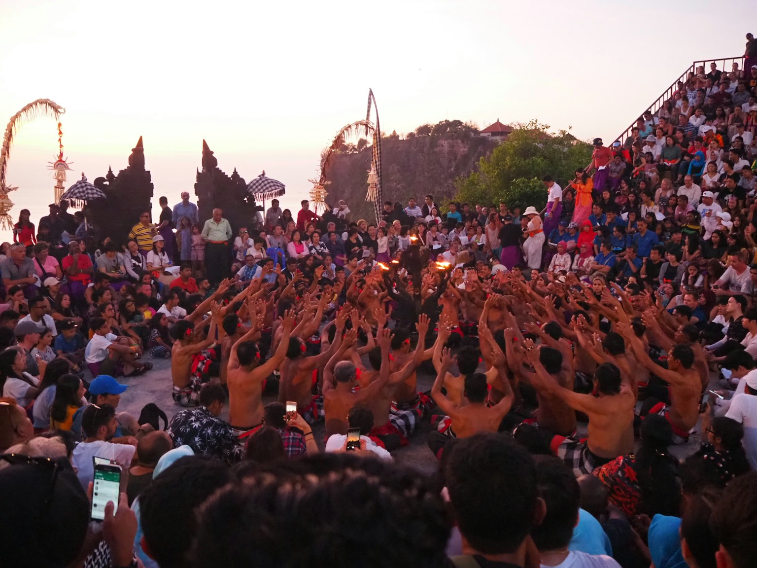Kelompok yang melakukan tarian api saat matahari terbenam di Bali dengan banyak penonton