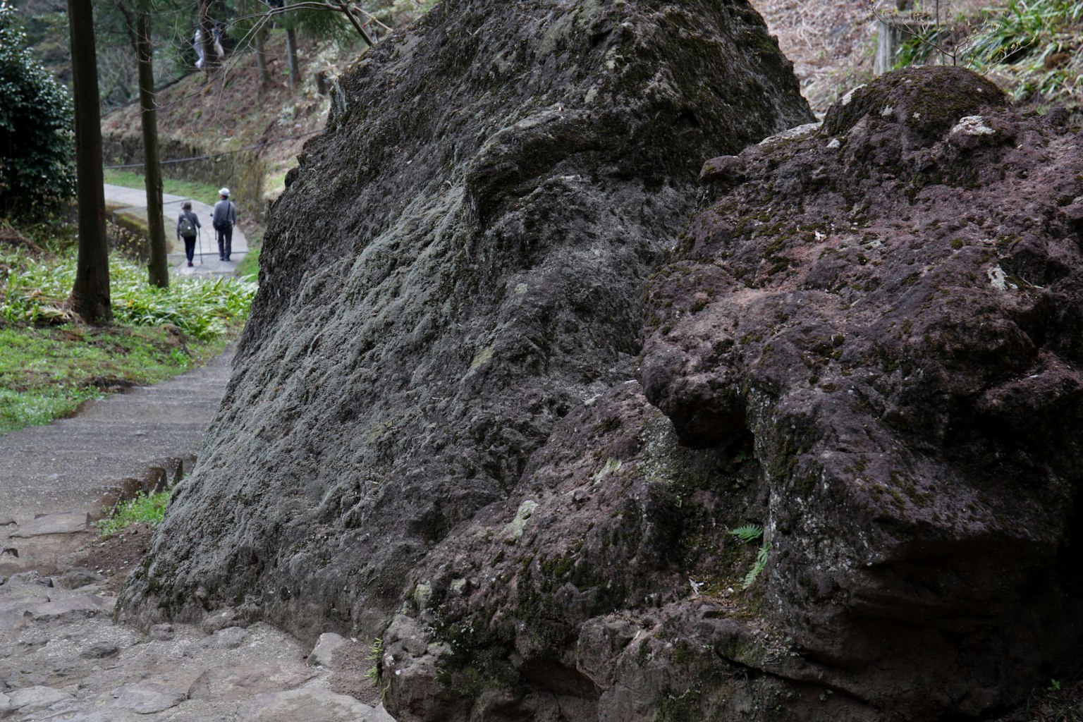 Paisaje con una gran roca y personas caminando por un sendero