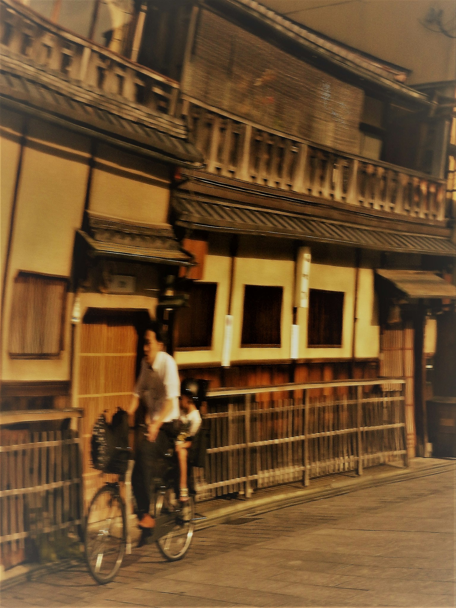 古い日本の街並みを背景に自転車に乗る男性