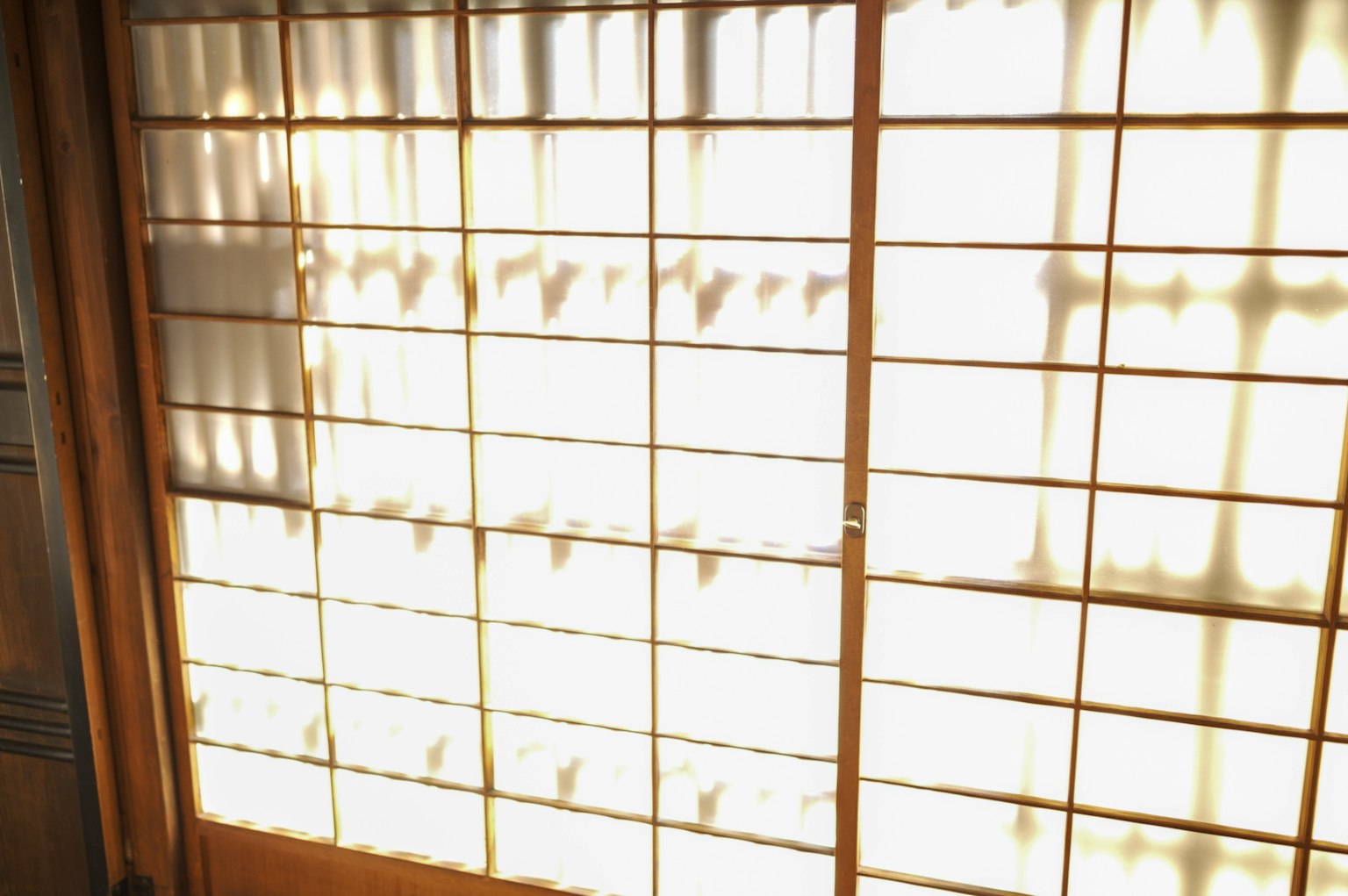Luce che filtra attraverso una finestra shoji creando ombre in una stanza giapponese tradizionale
