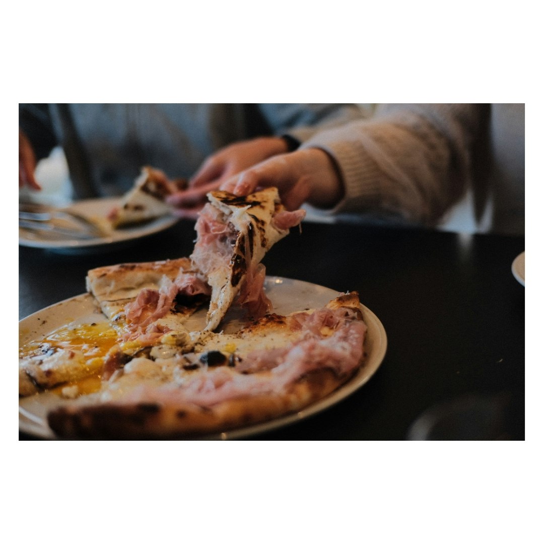 ピザのスライスを手でちぎっている食卓の一場面