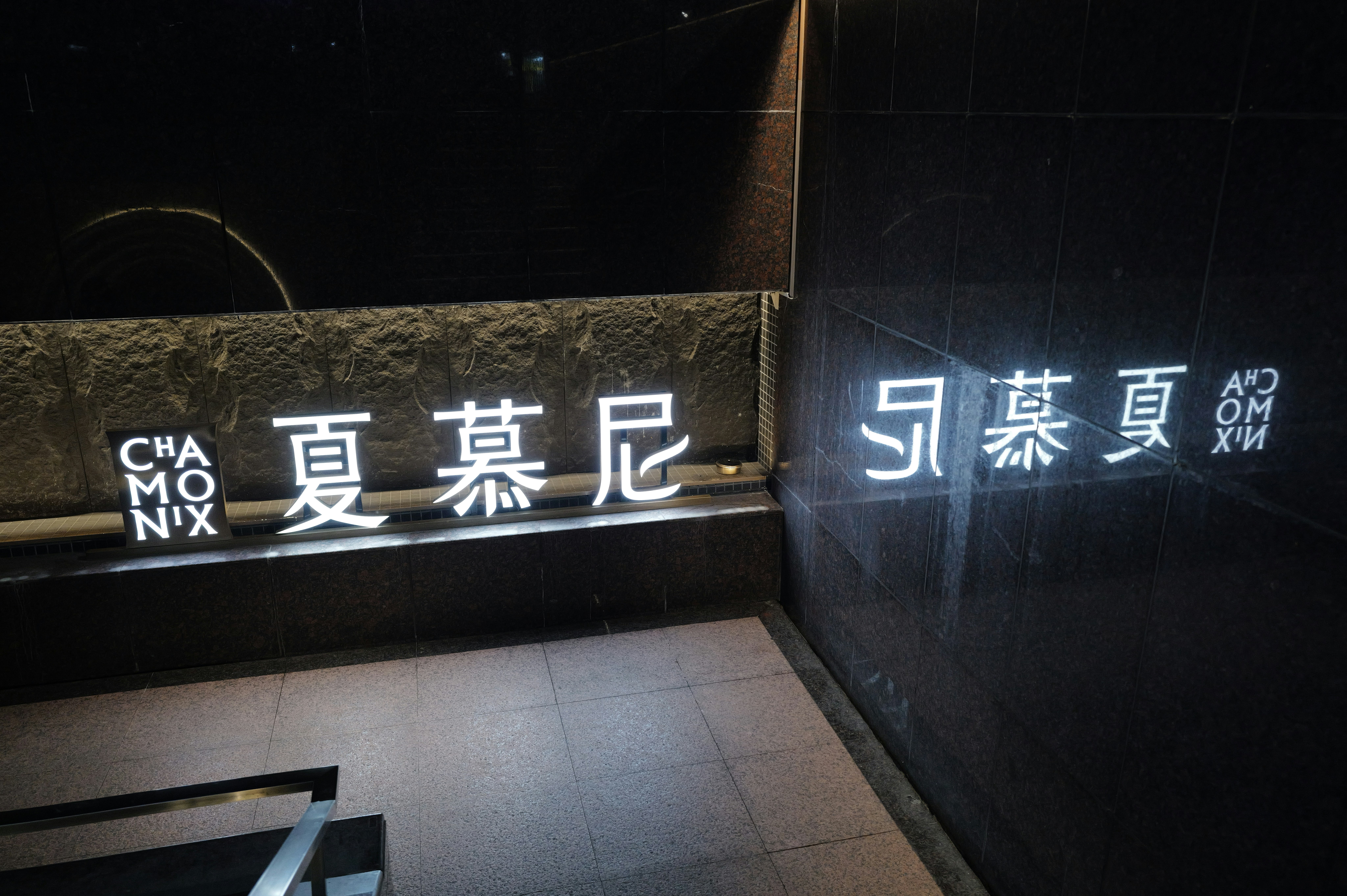 暗い壁面に並ぶ中国語の看板と階段のある路地