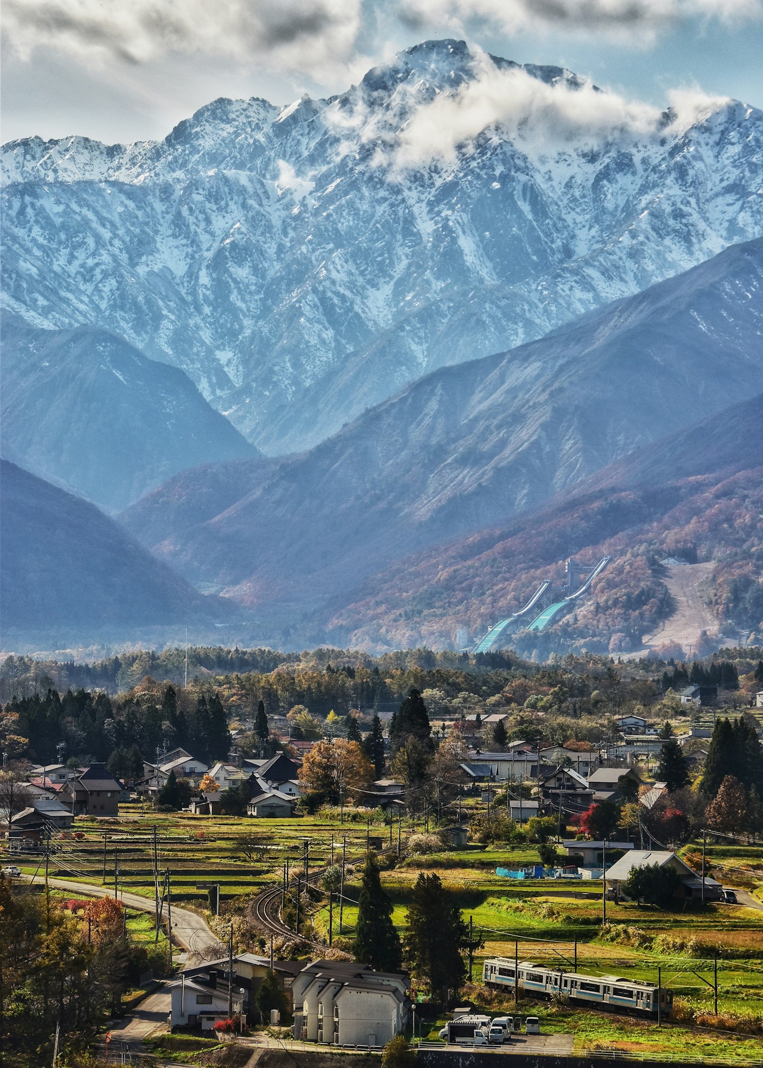 Vista panoramica di montagne innevate e campi verdi