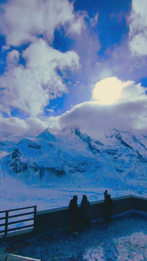 雪に覆われた山々と青い空を背景にした観光客のシルエット