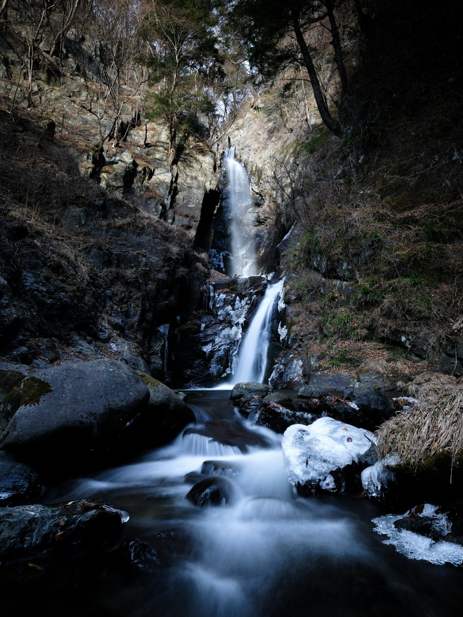 A smooth waterfall cascading through a mountainous landscape