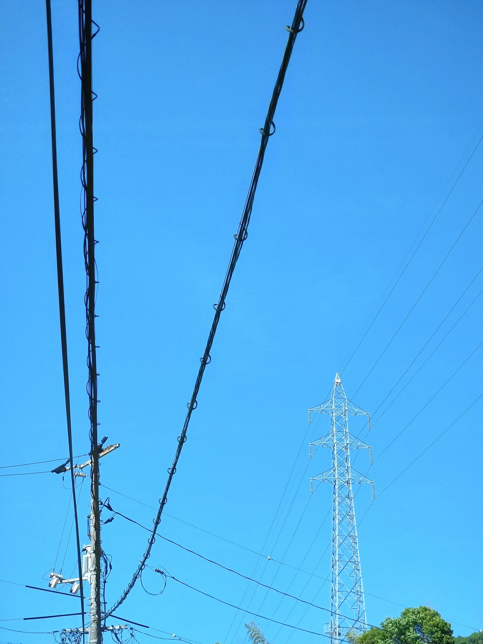 Cables eléctricos y una torre de alta tensión contra un cielo azul claro