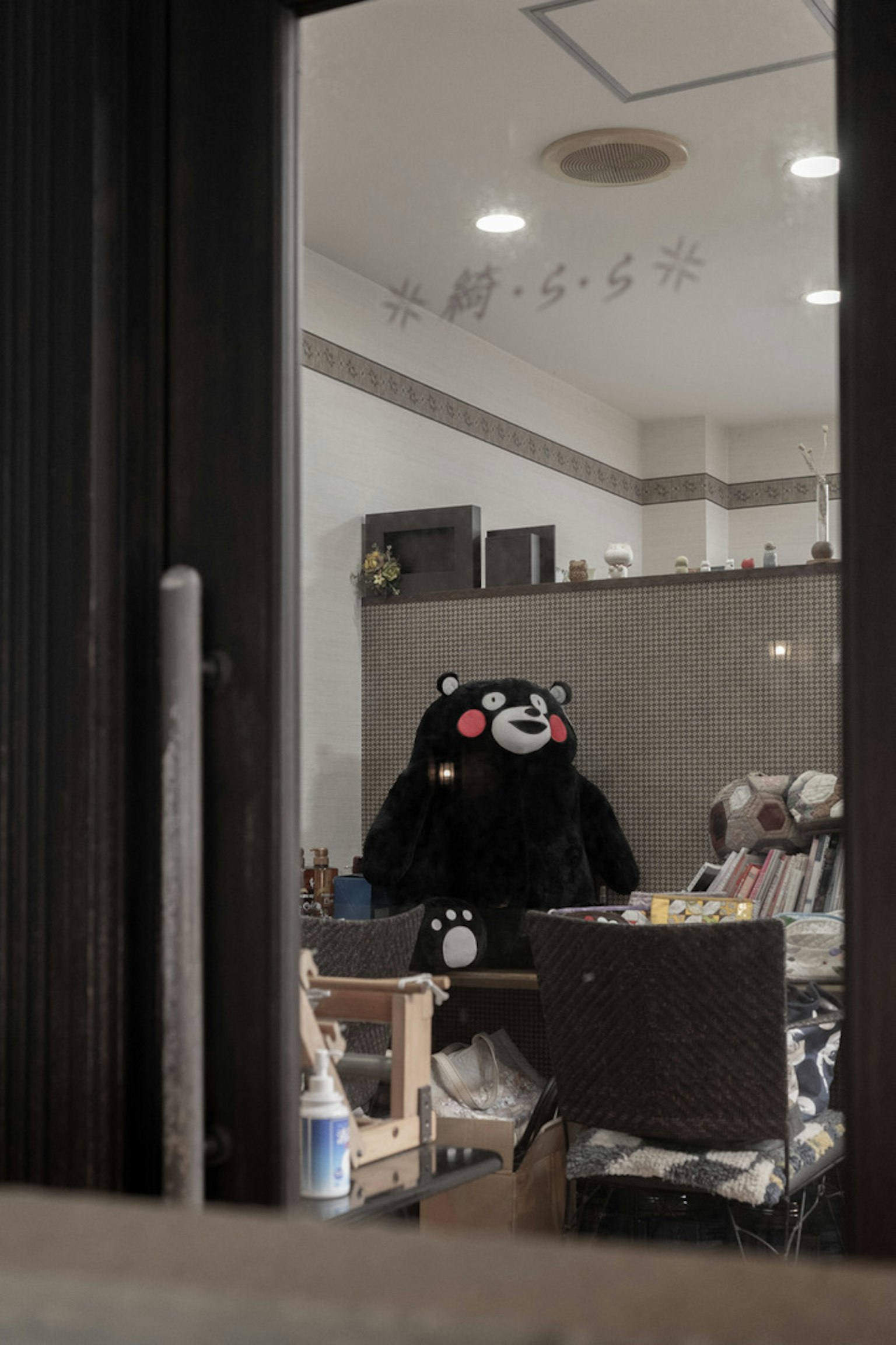 Una stanza con un costume da orso nero seduto visibile attraverso una finestra
