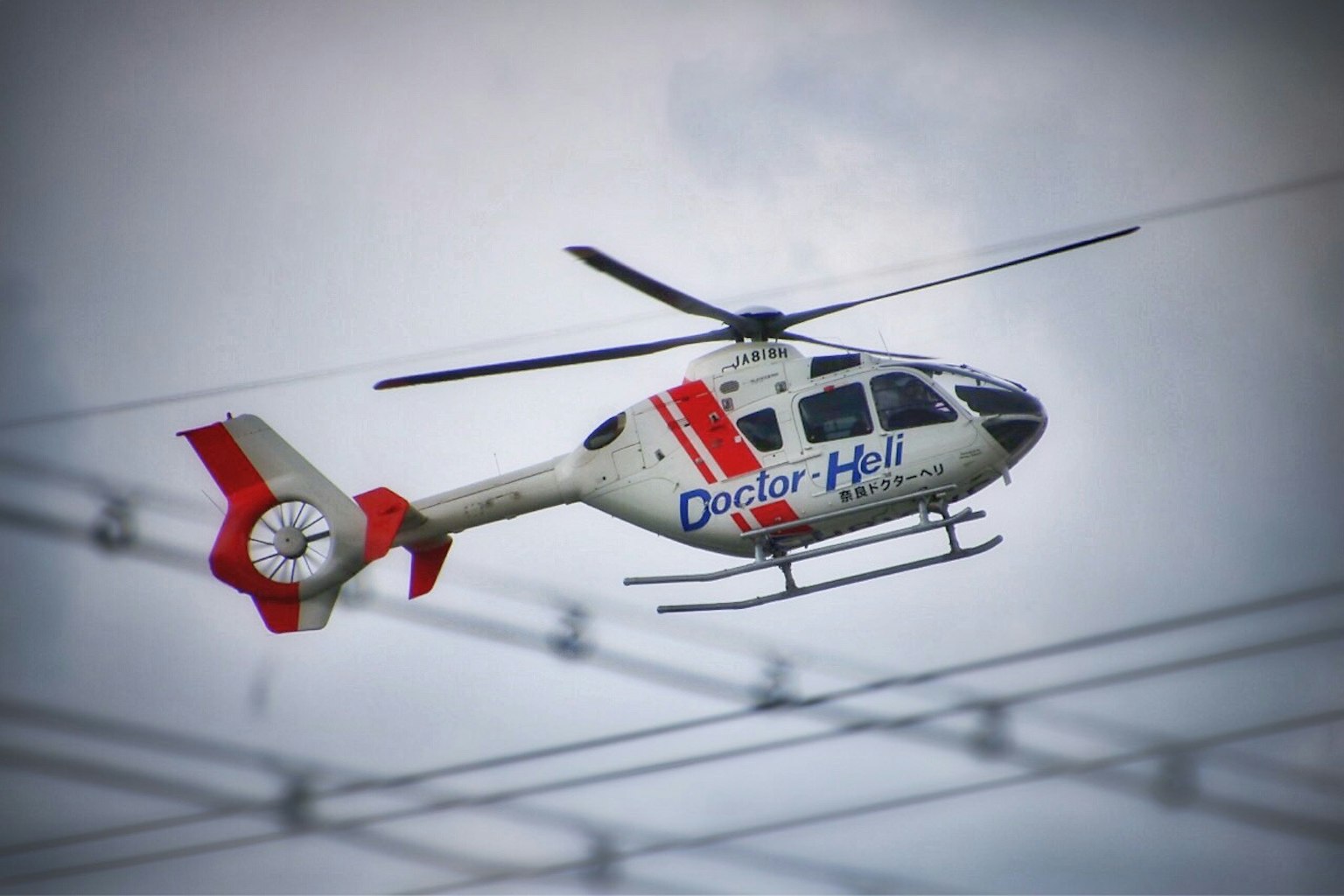 Helikopter merah dan putih terbang di langit