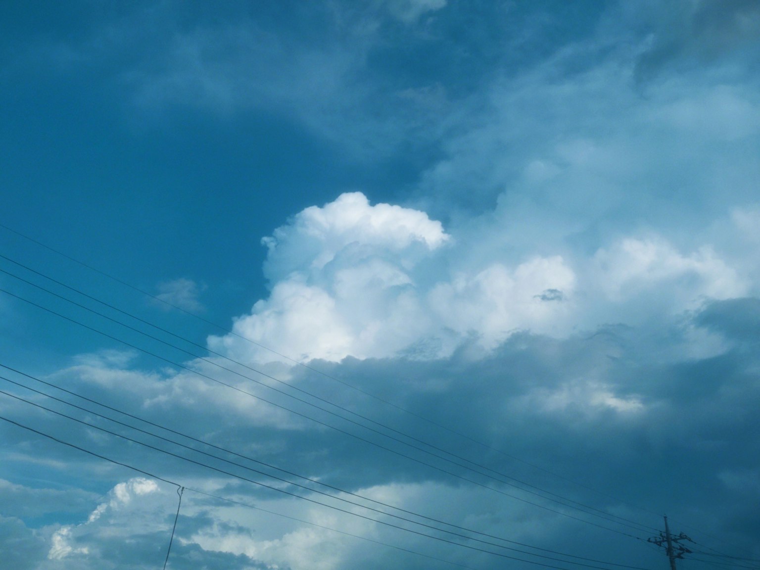 Langit biru dengan awan dan saluran listrik yang terlihat