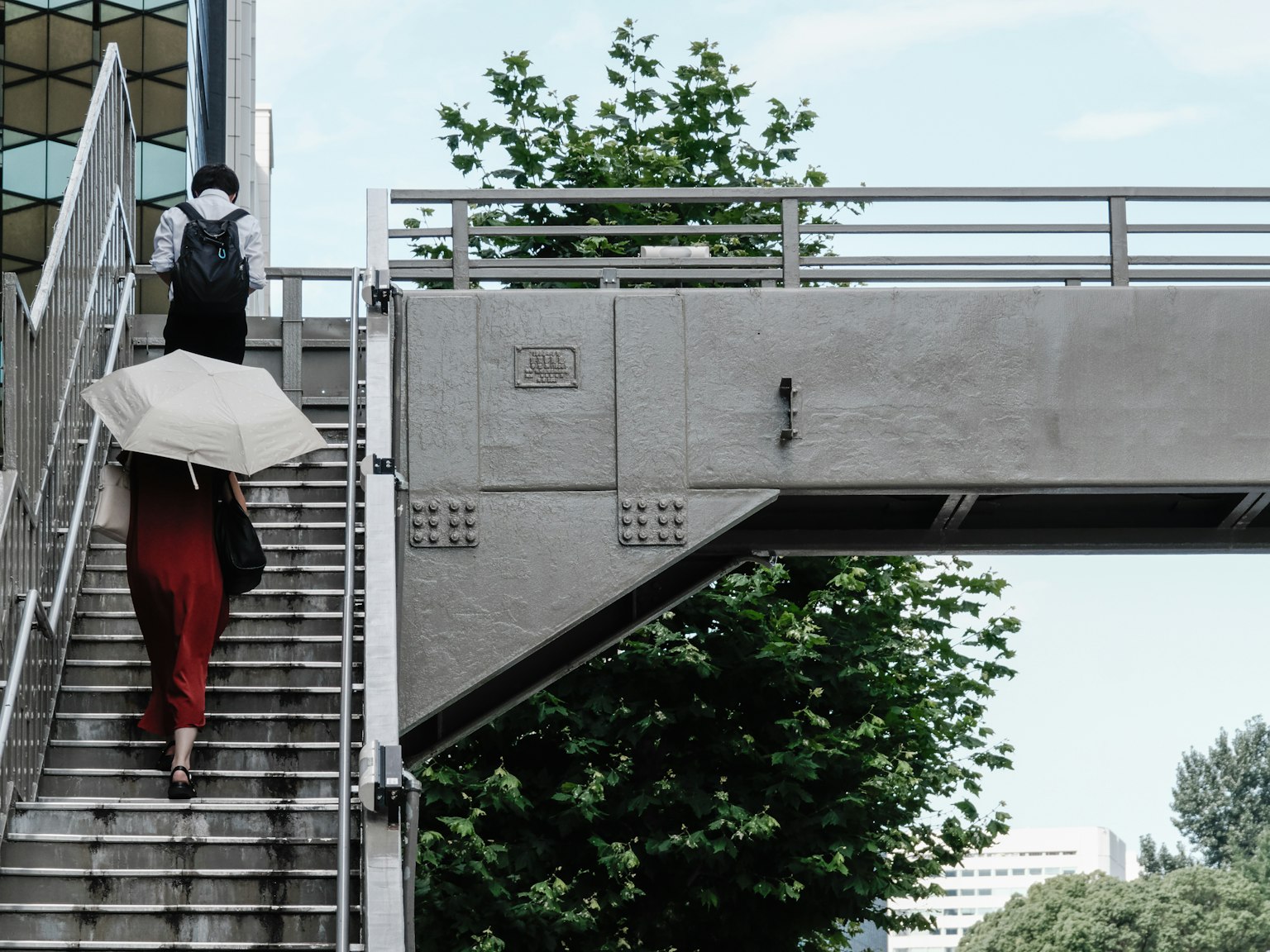 Una donna in abito rosso che sale le scale mentre un uomo porta un ombrello