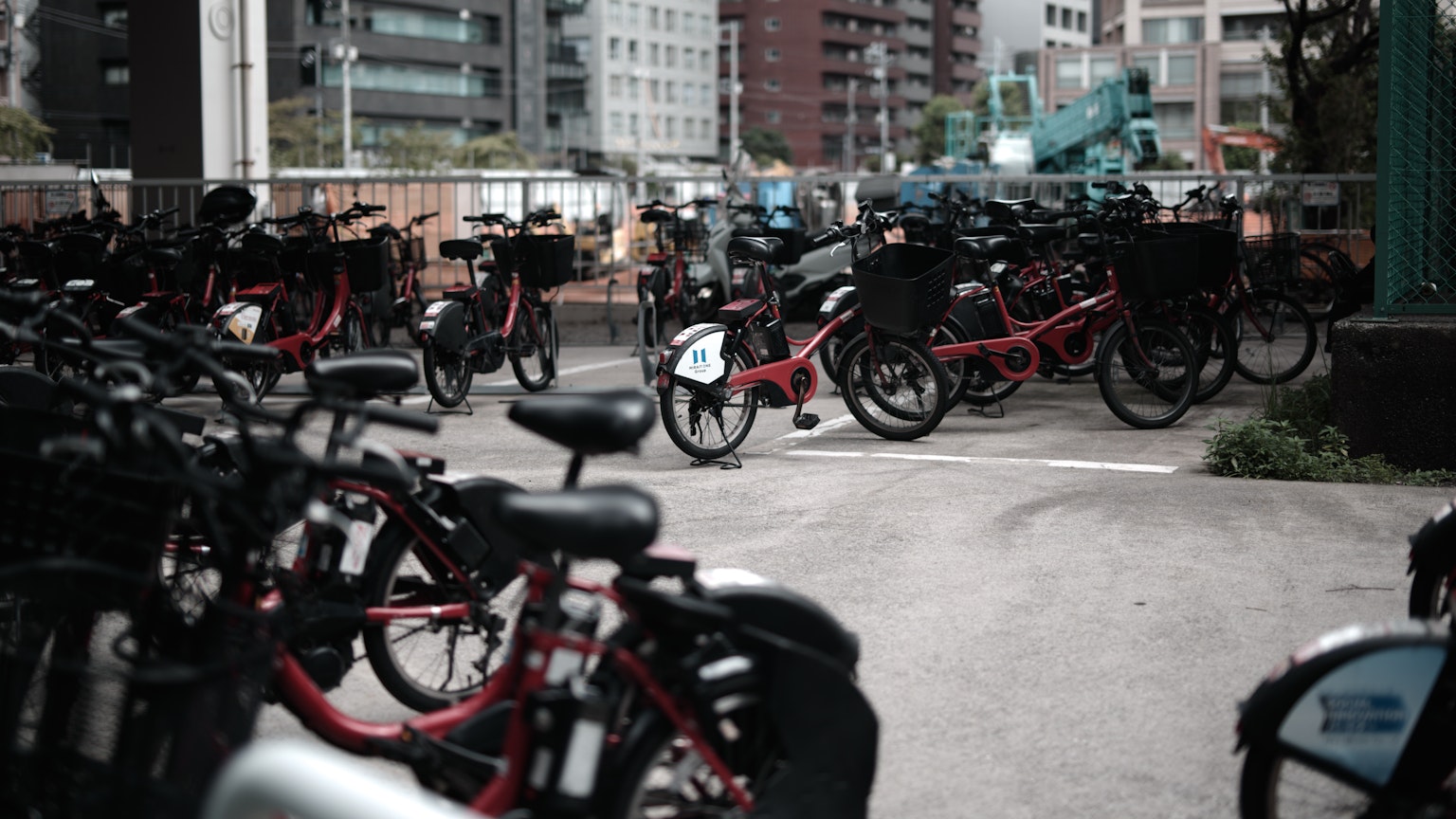 Bicycle parking area filled with bikes prominently featuring red bicycles in an urban setting