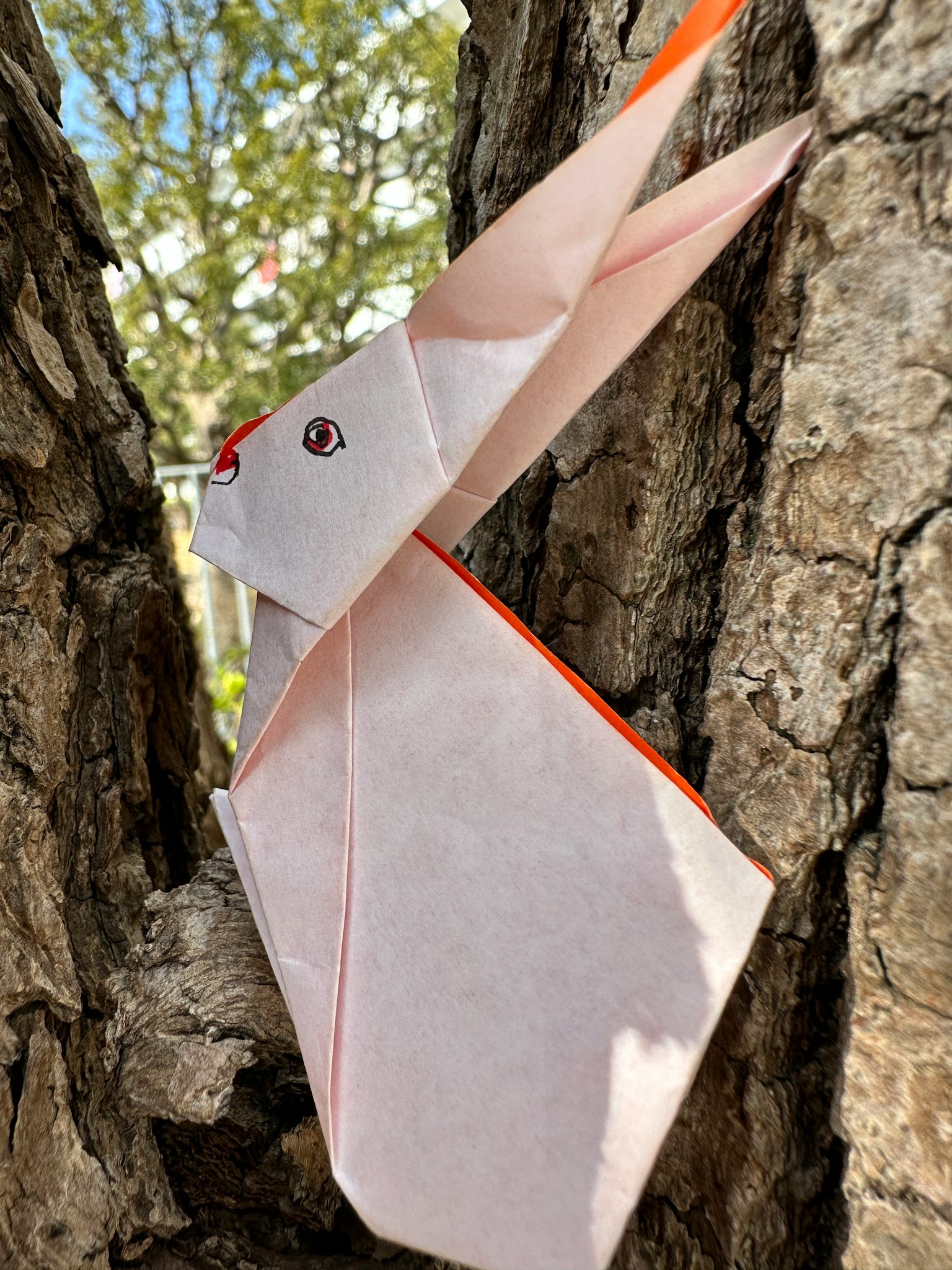 Coniglio in origami appoggiato a un tronco d'albero